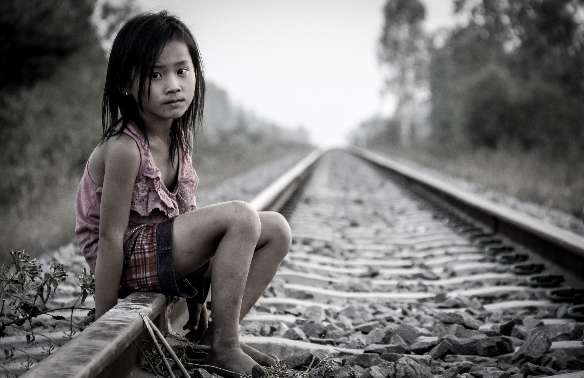 Young girl sitting on railroad tracks HD Wallpaper