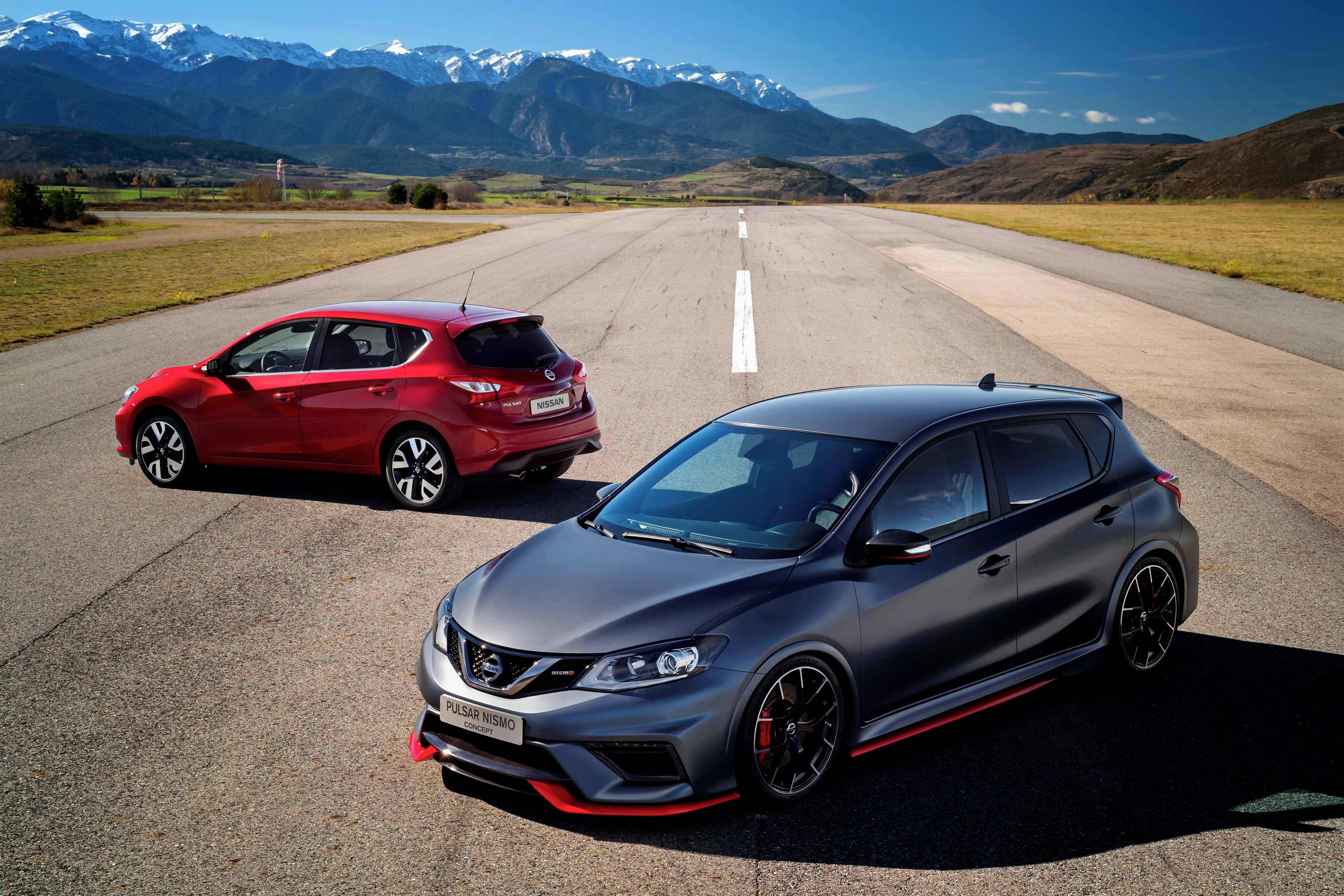 Two Nissan Pulsar Nismo Concept cars on a road with mountains HD Wallpaper