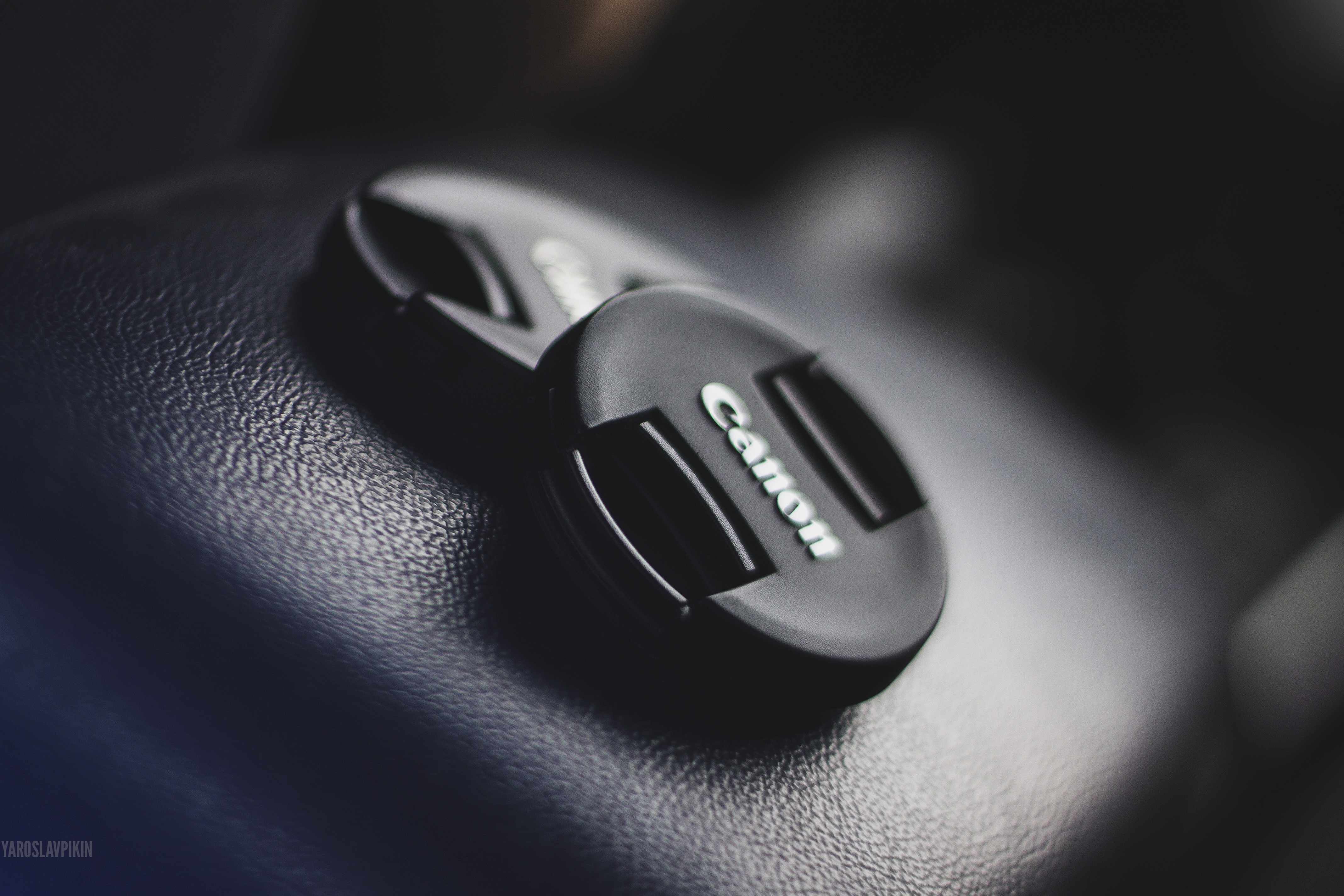 Canon camera lens cap on textured surface HD Wallpaper