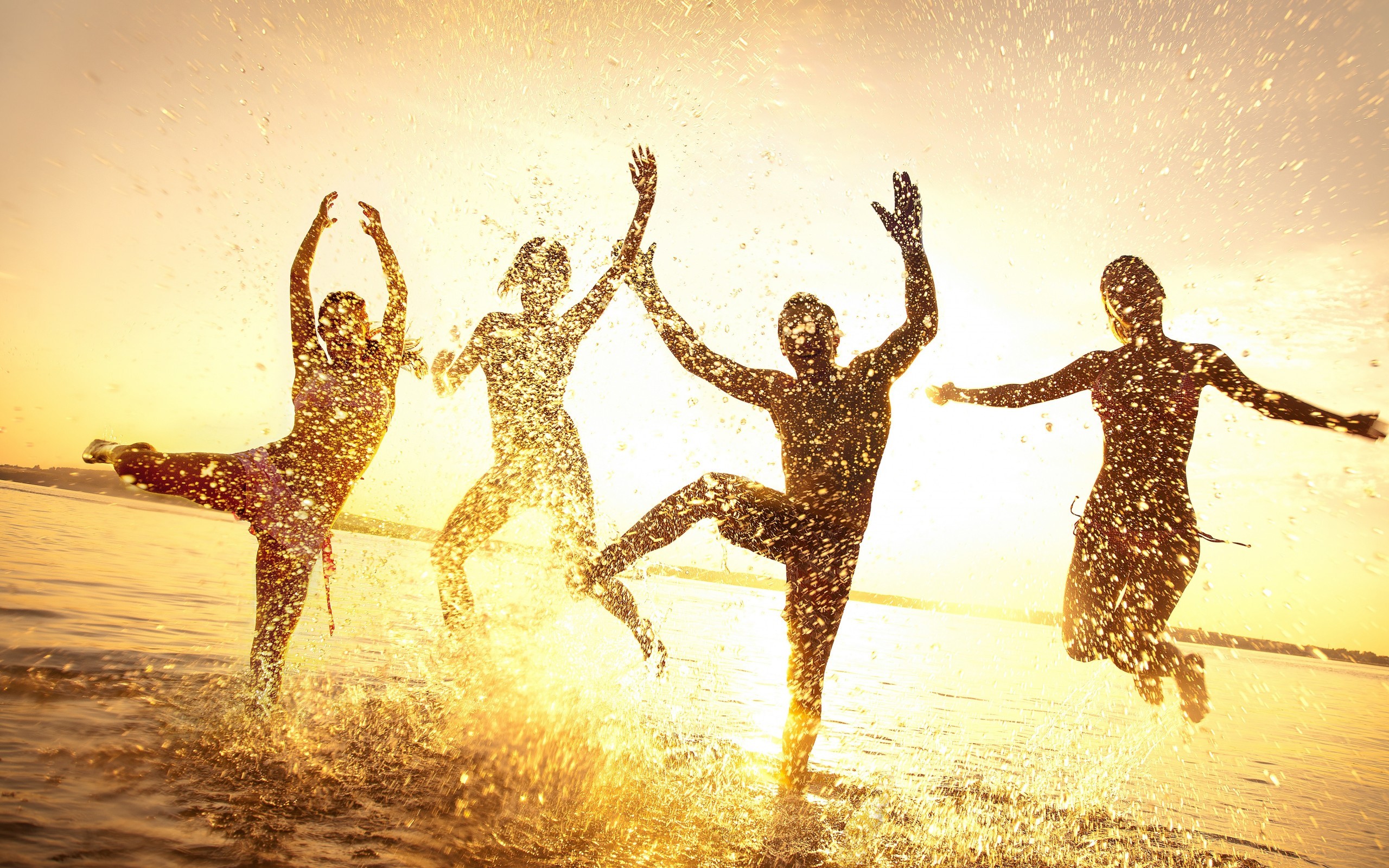 Four people jumping in water with splashes at sunset HD Wallpaper