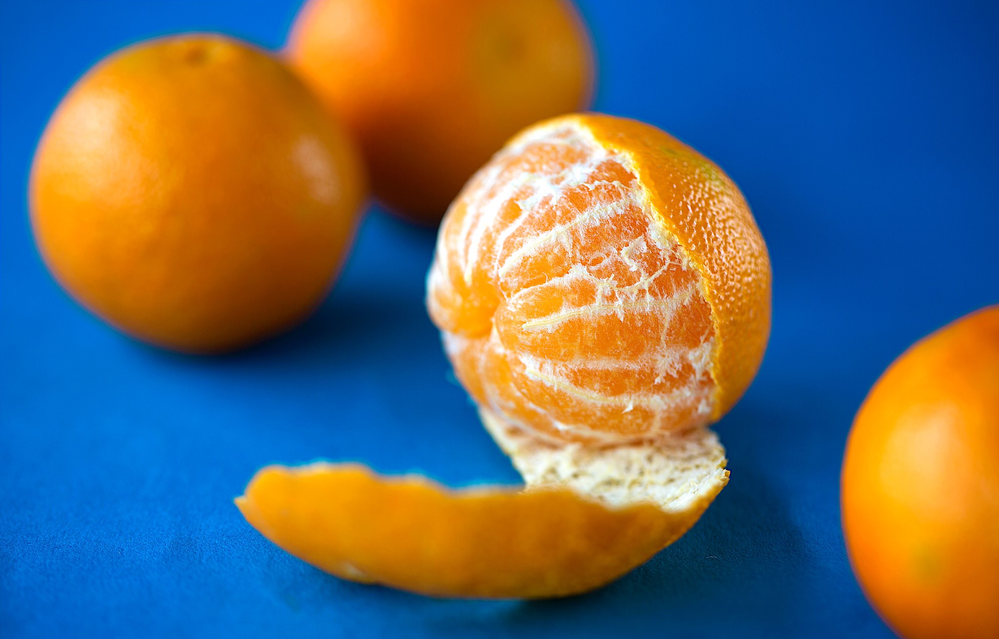 Peeled Mandarin orange on a blue surface HD Wallpaper
