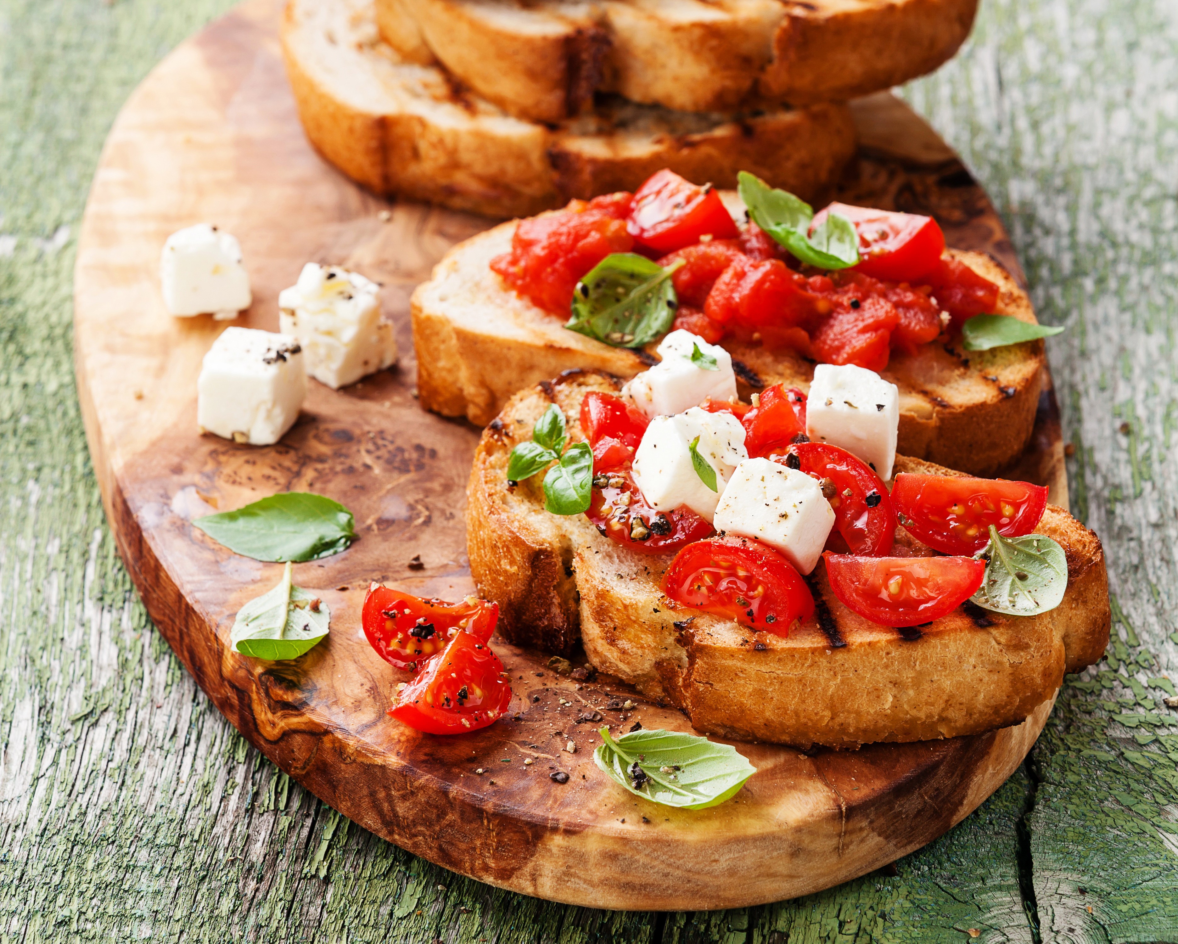Bruschetta with tomatoes, feta, and basil on a wooden board HD Wallpaper