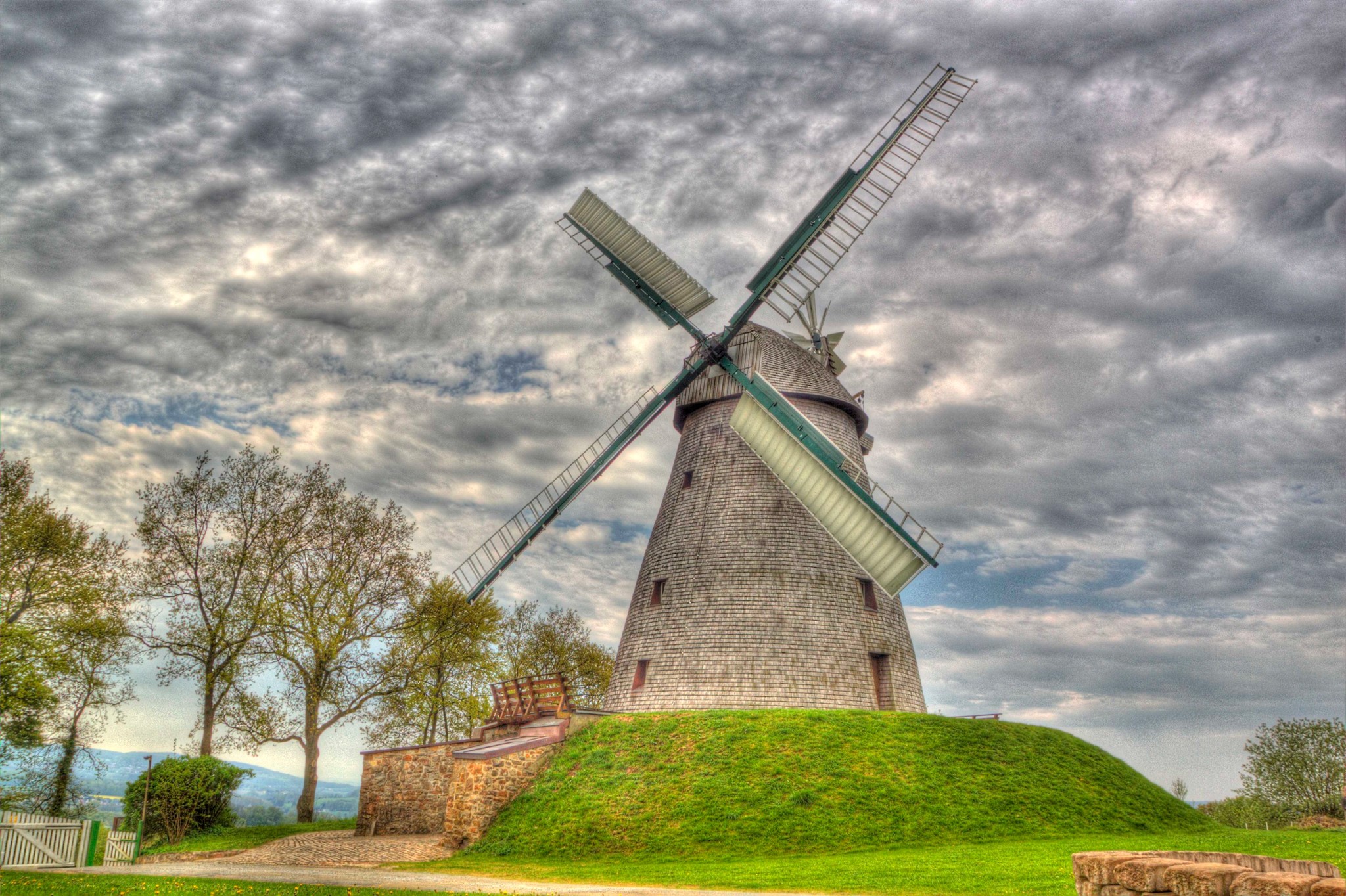 Windmill on a grassy hill under cloudy sky HD Wallpaper
