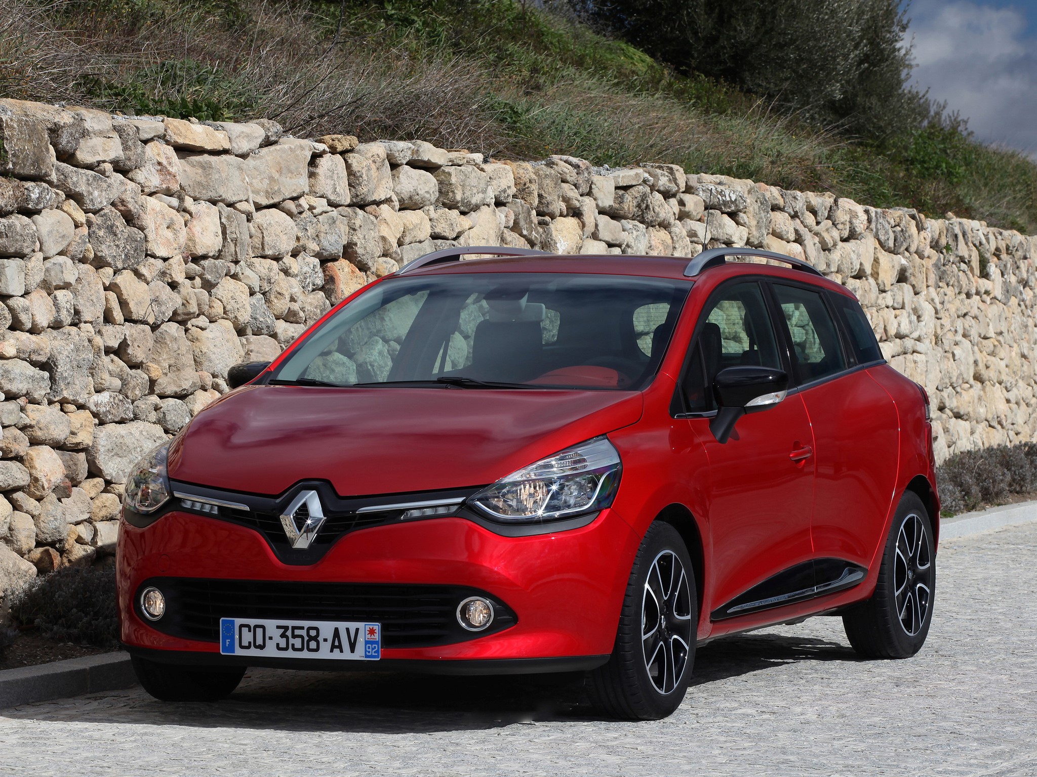 Red Renault Clio Estate car parked in front of a stone wall HD Wallpaper