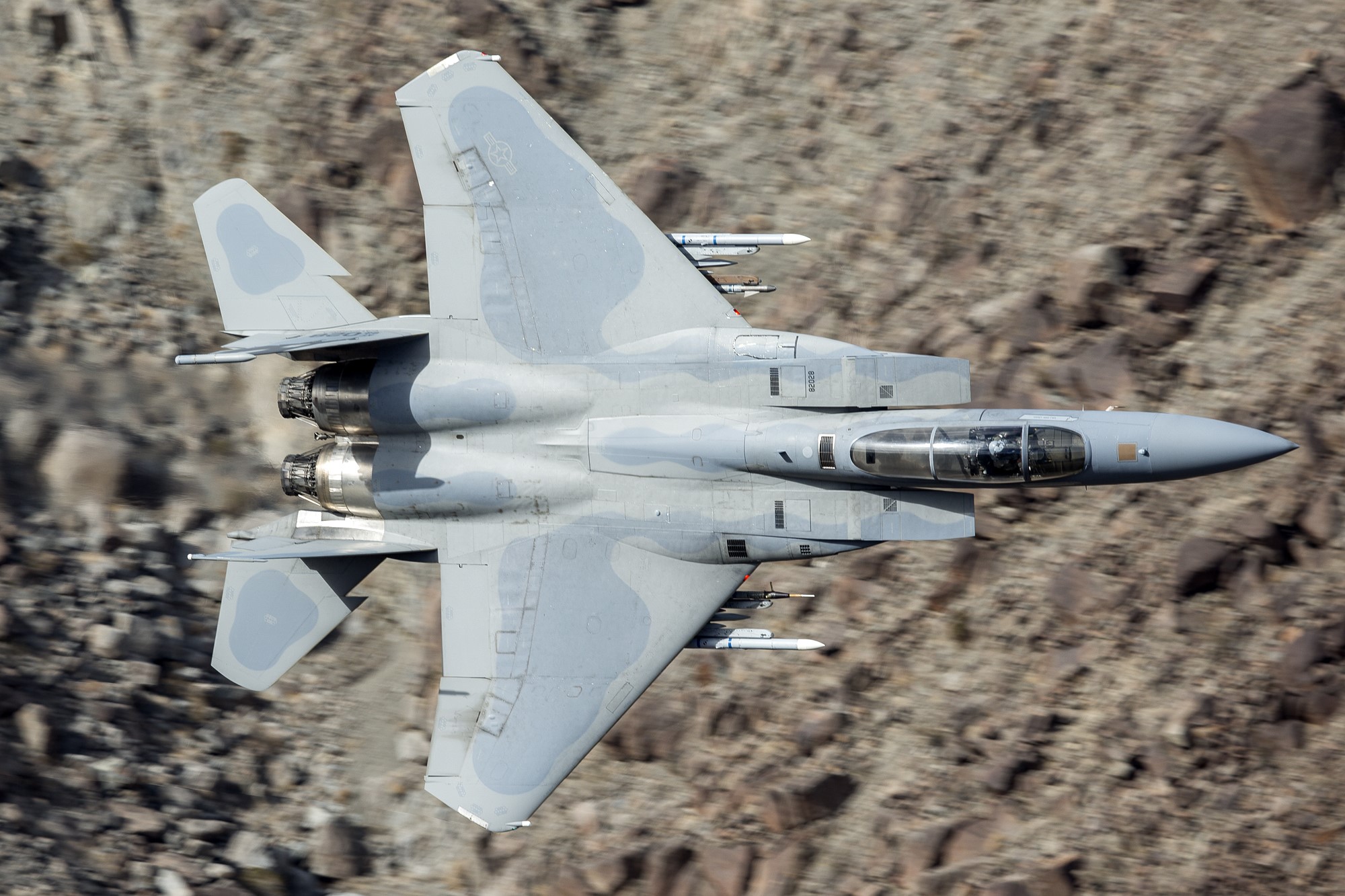 F-15 Eagle fighter jet flying over rocky terrain HD Wallpaper