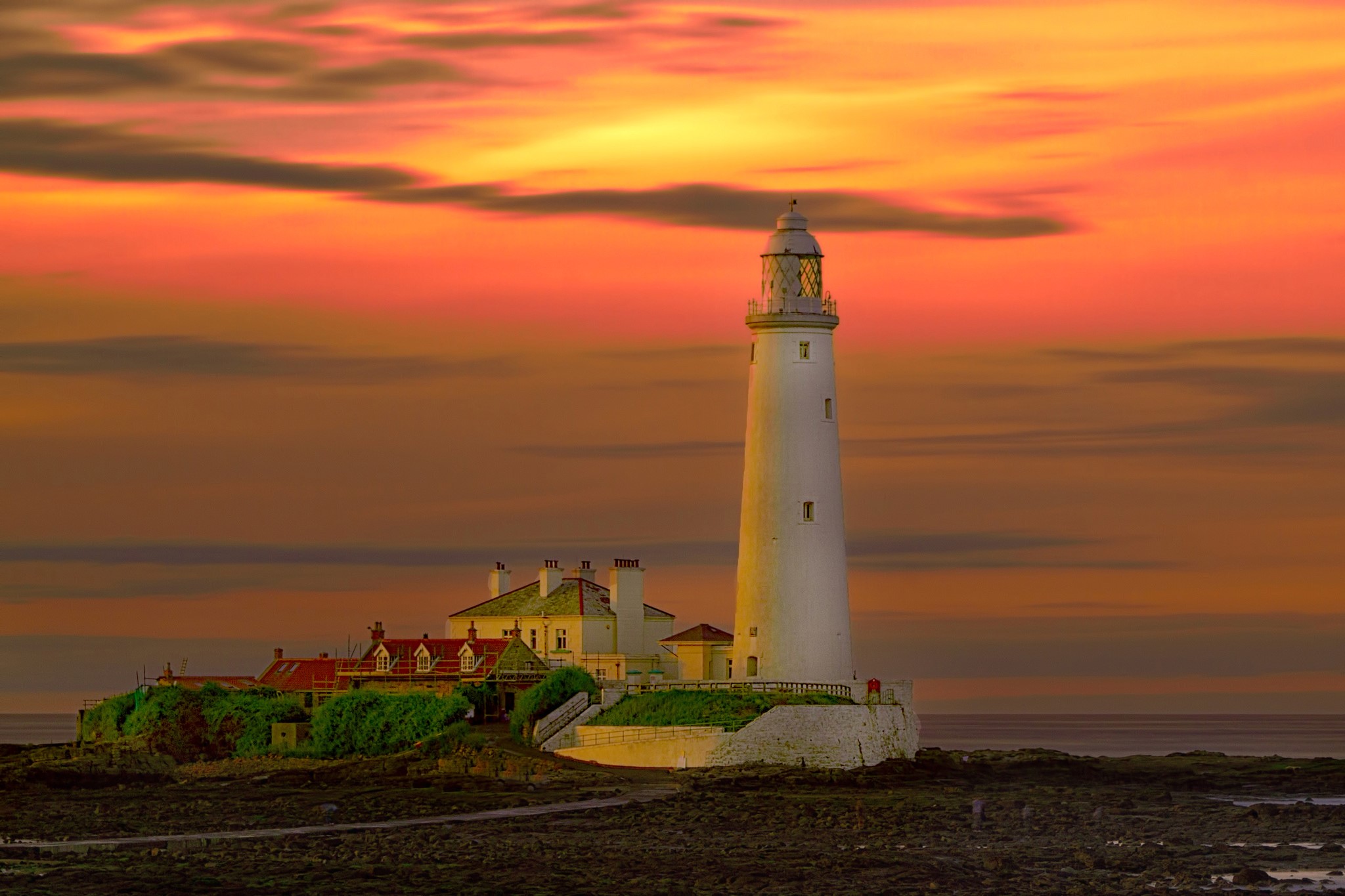White lighthouse on rocky island at sunset HD Wallpaper