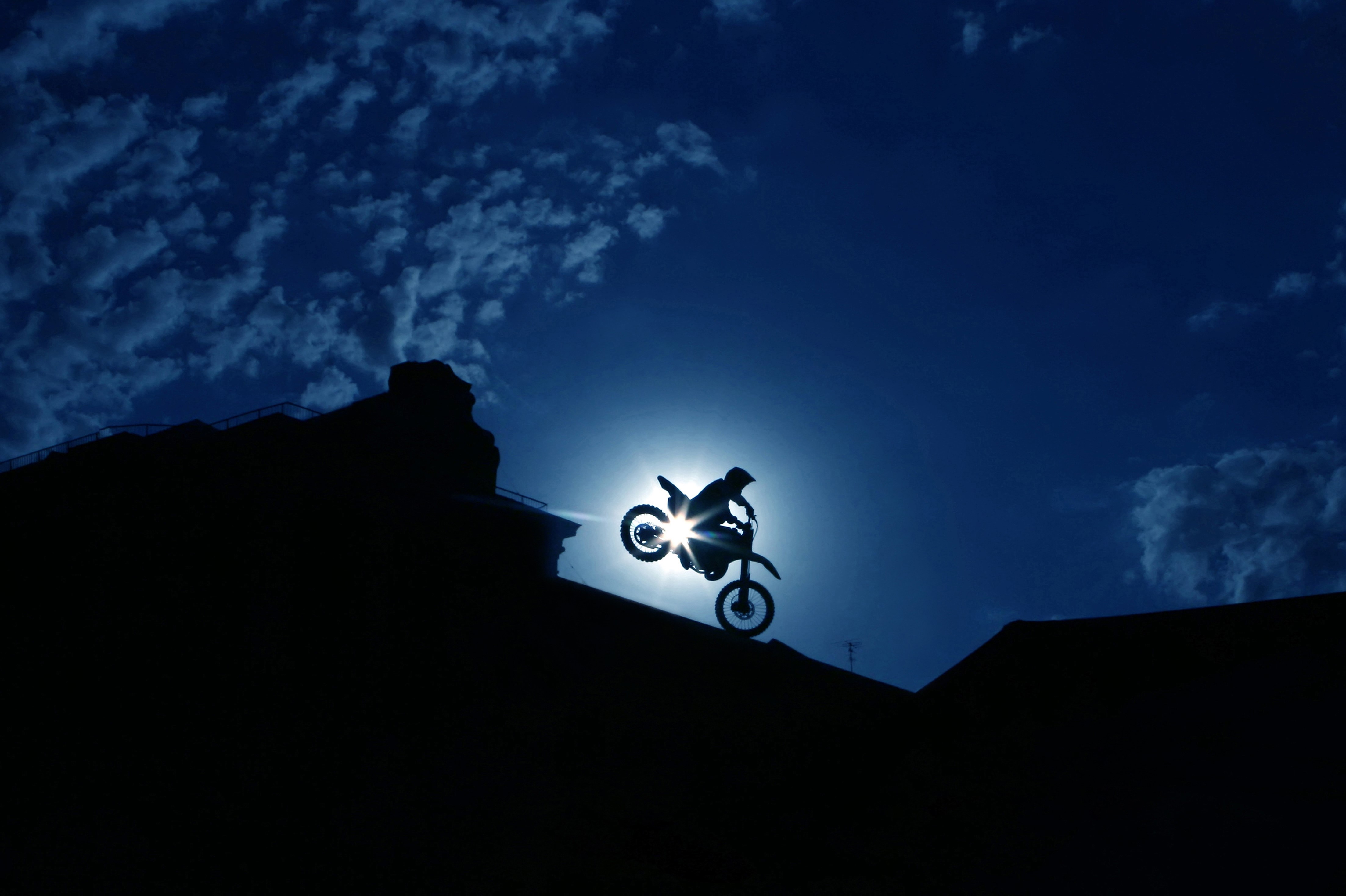 Motorcyclist performing a stunt against the sun HD Wallpaper