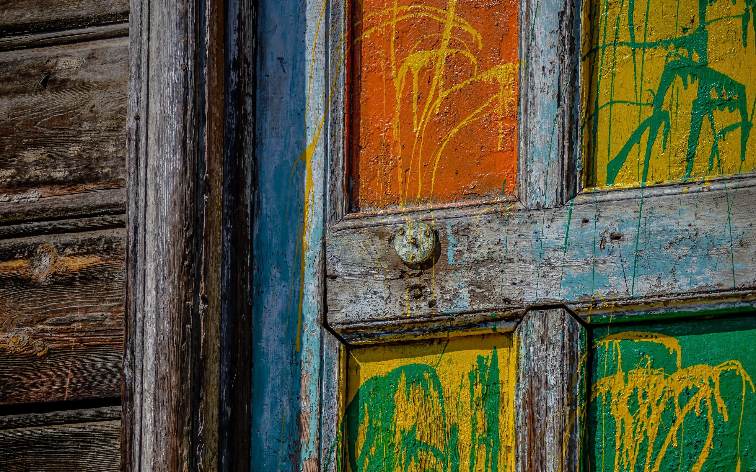 Close-up of a weathered wooden door with colorful paint splatters HD Wallpaper