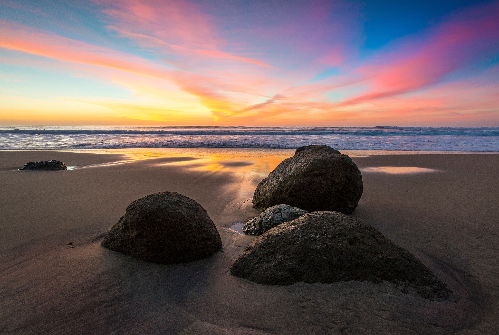 Sunset over the ocean with rocks on the beach HD Wallpaper