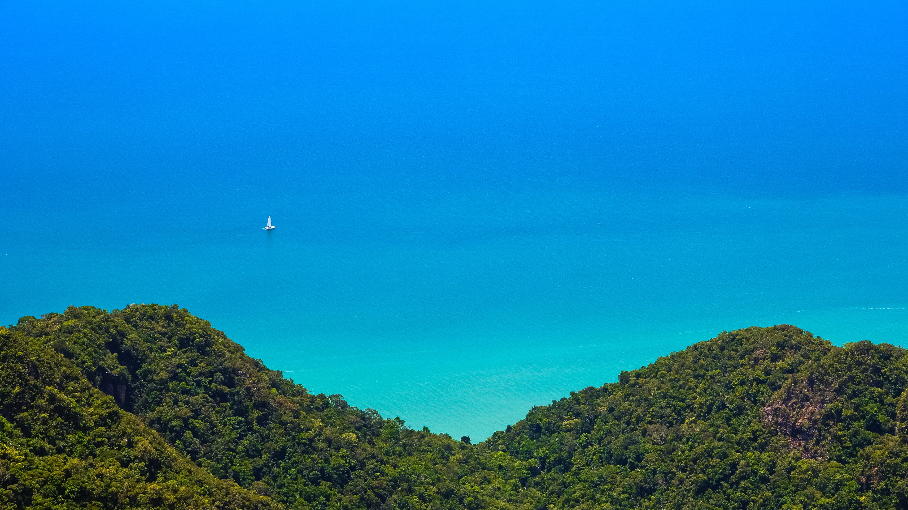 Sailboat on blue ocean with green islands HD Wallpaper