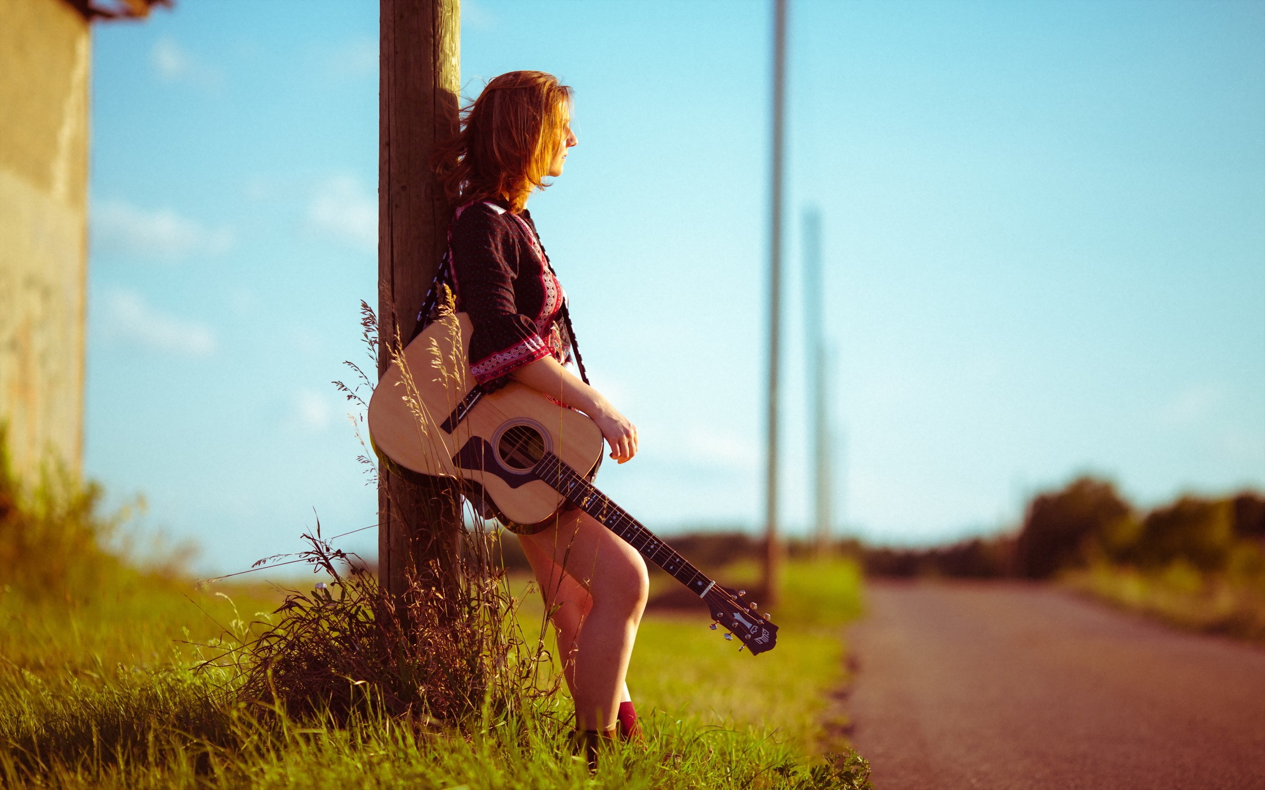 Girl with guitar leaning on pole by road HD Wallpaper