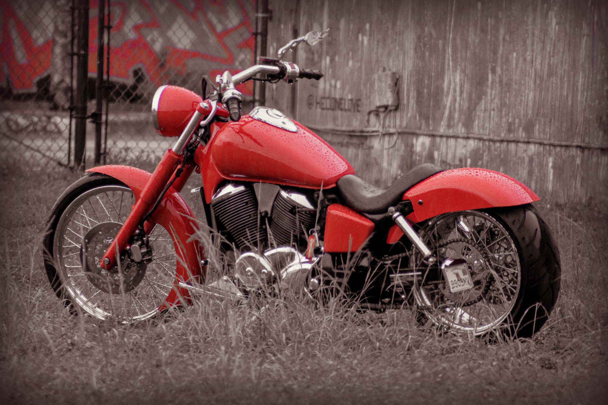 Red motorcycle parked in grass near graffiti wall HD Wallpaper