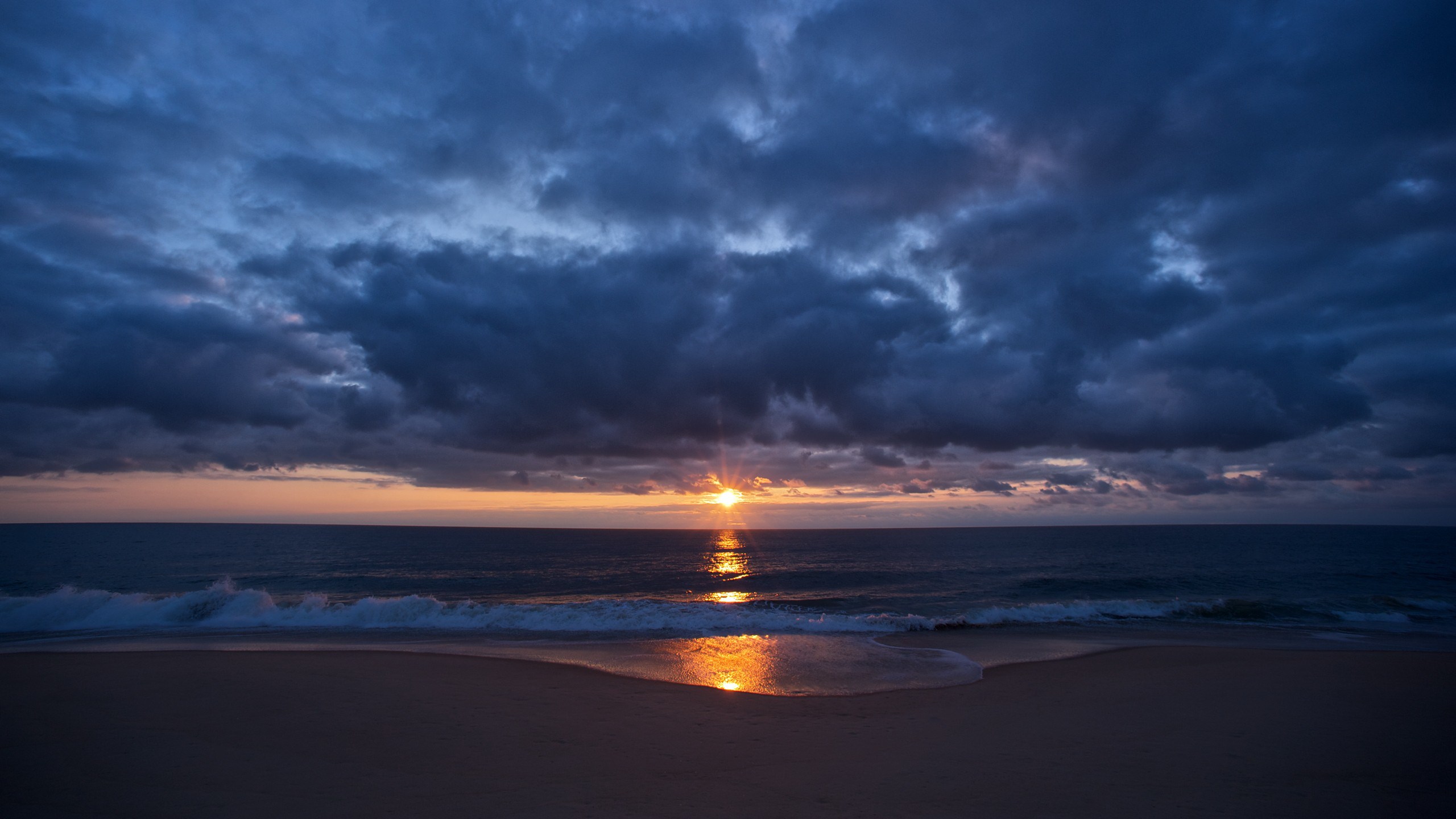 Sunset over the ocean with dark clouds HD Wallpaper