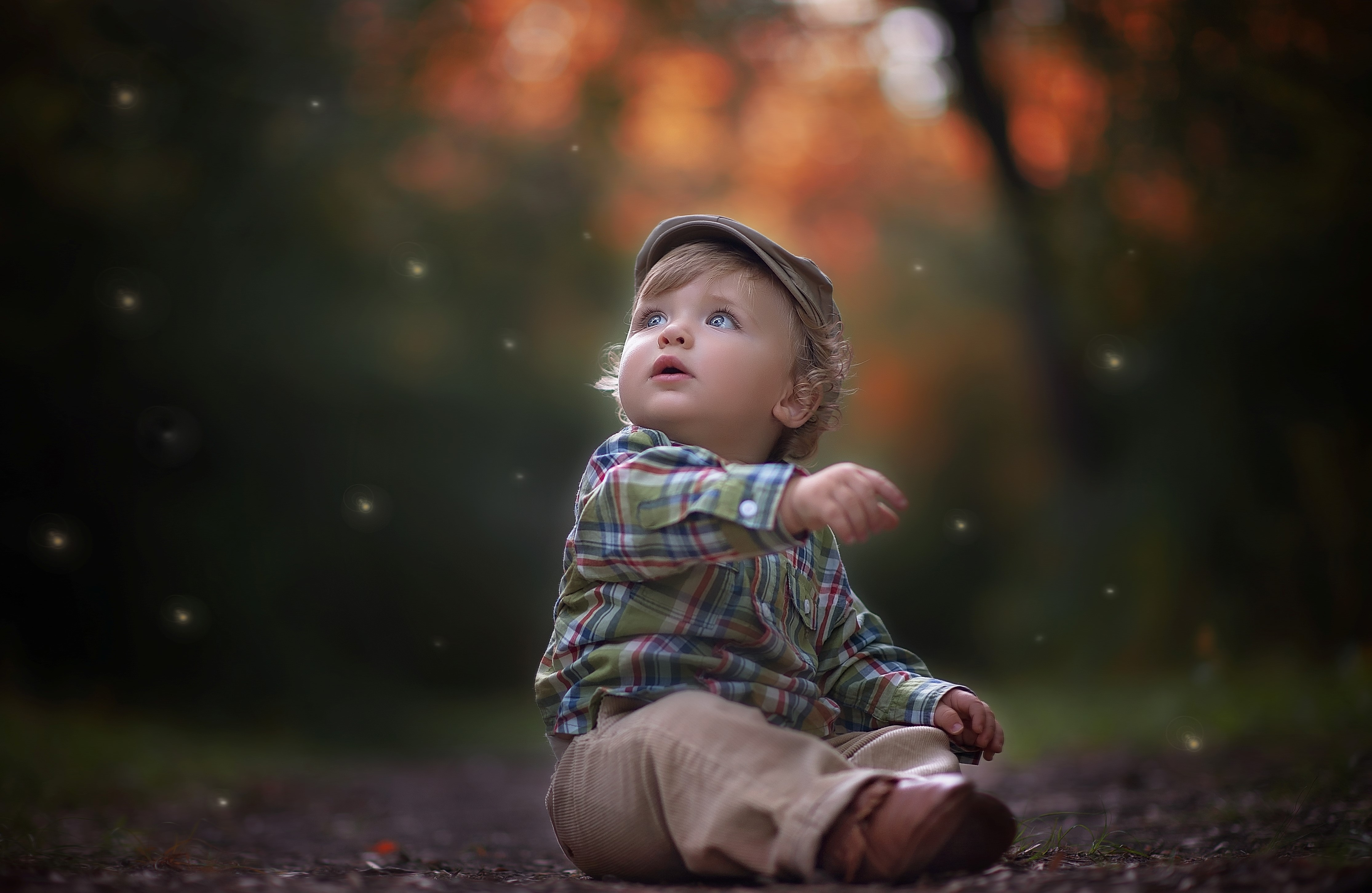 Baby boy sitting outdoors wearing a cap and plaid shirt HD Wallpaper