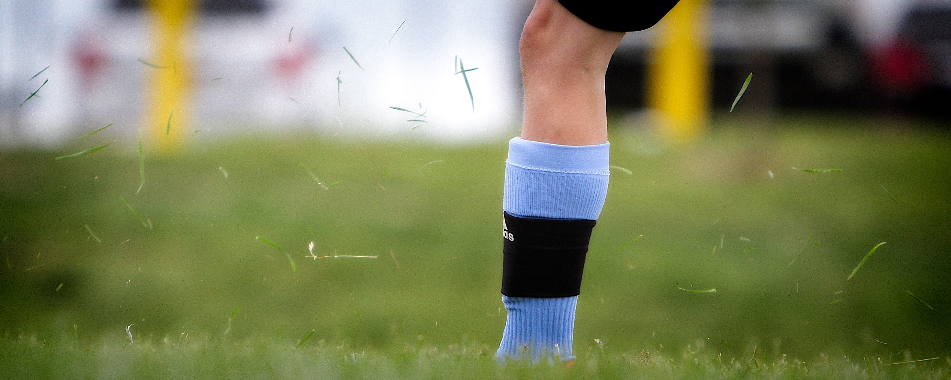 Soccer player's leg with grass flying HD Wallpaper