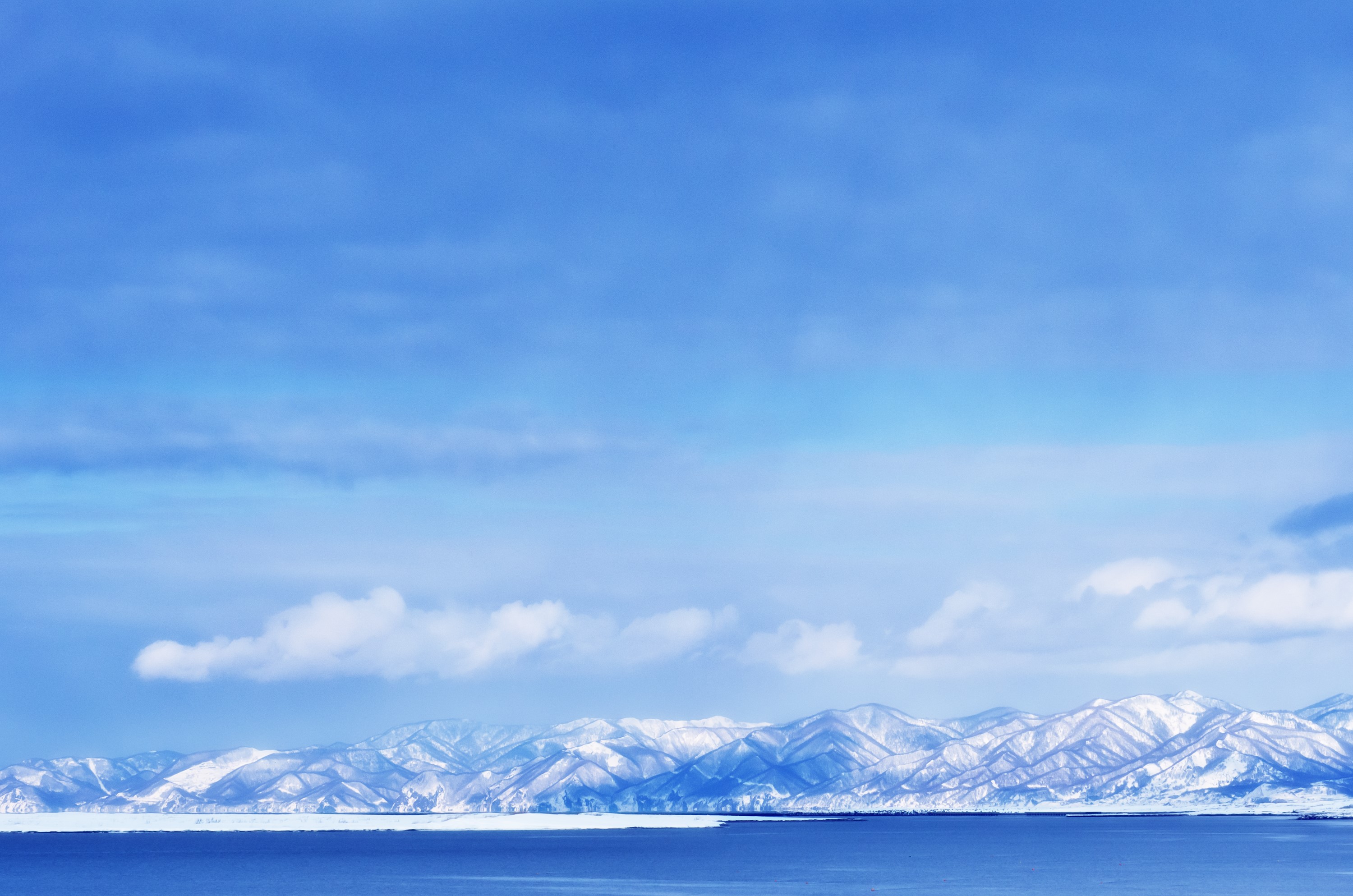 Snow-capped mountains in Hokkaido, Japan, under a blue sky HD Wallpaper