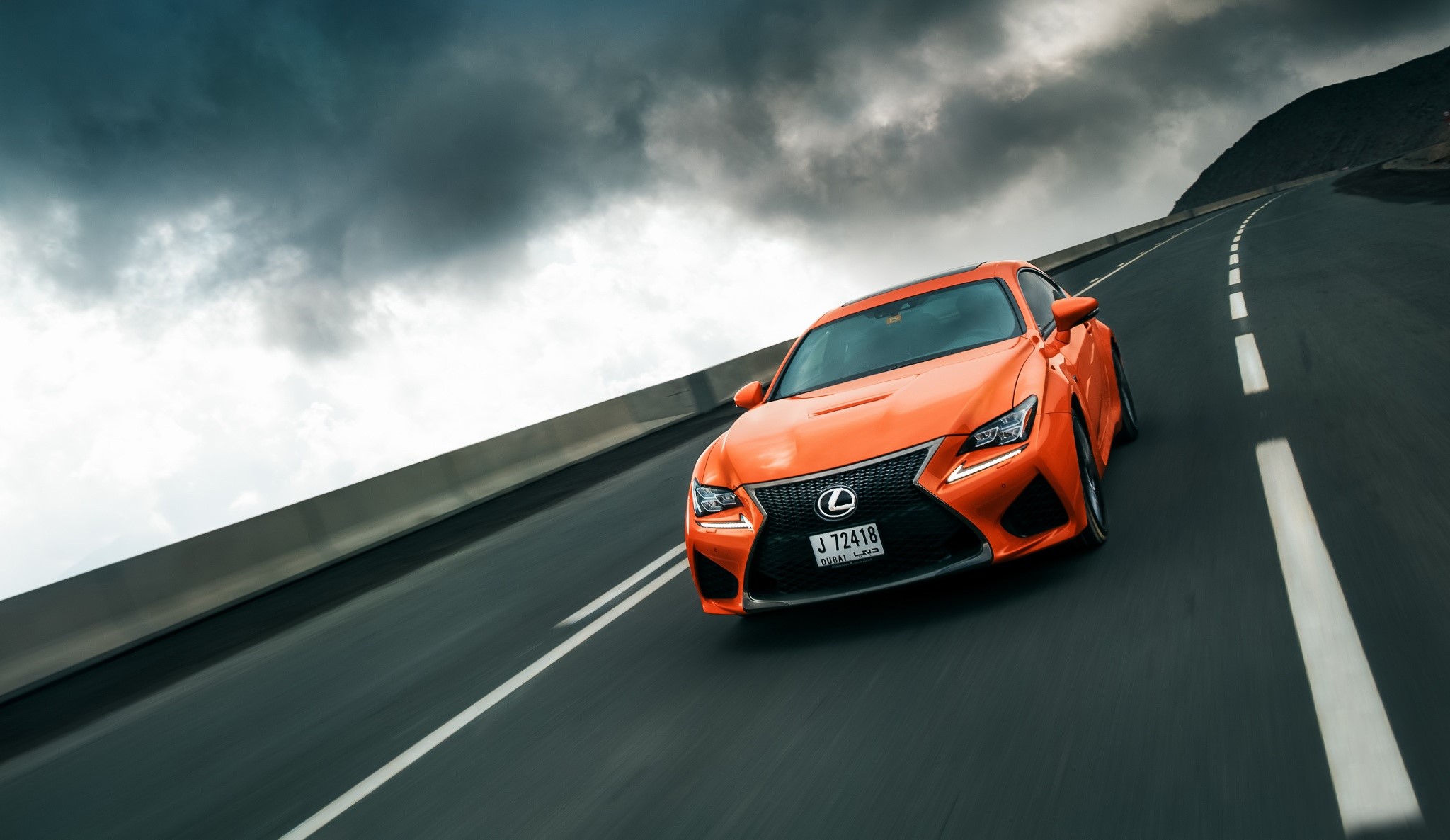 Orange Lexus RC F driving on a winding road HD Wallpaper