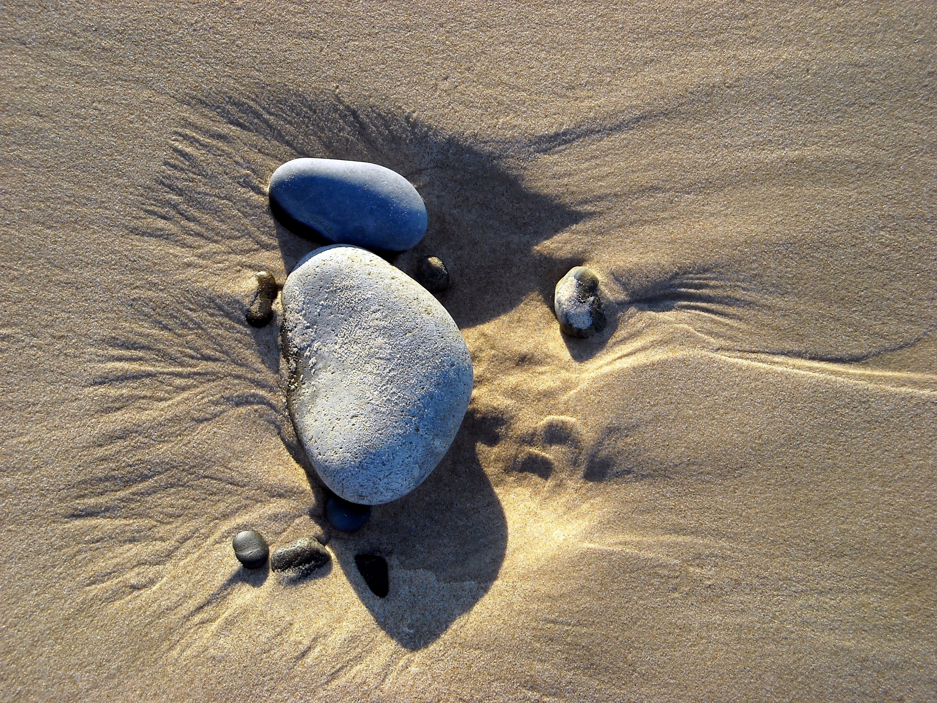 Smooth stones on wet sand with ripples HD Wallpaper