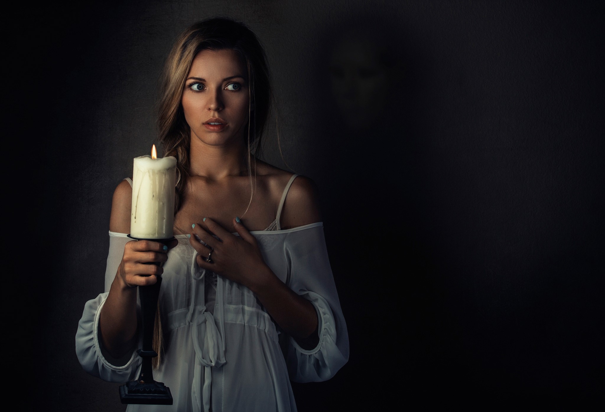 Woman holding a candle with a shadowy figure behind her HD Wallpaper