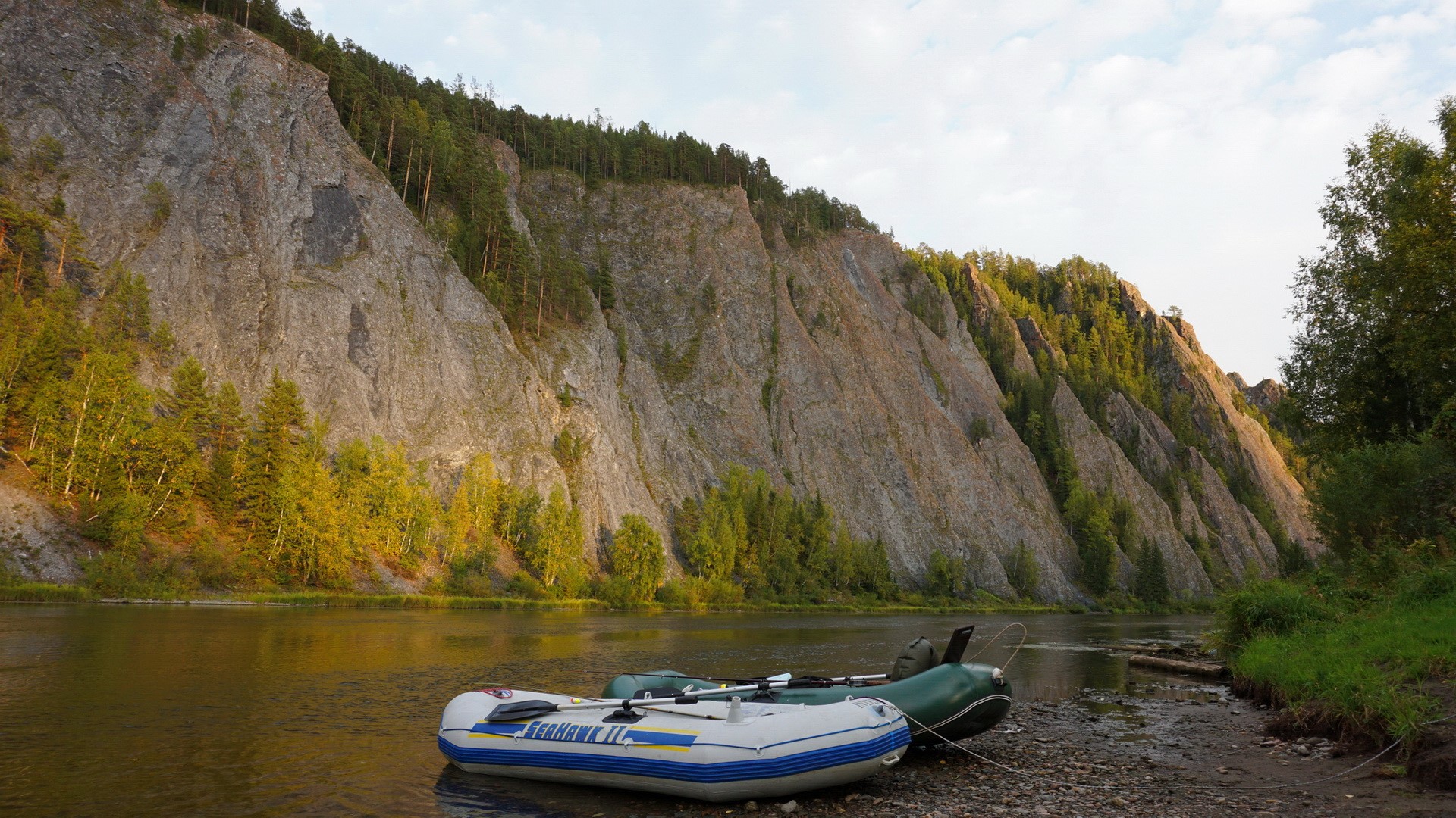 Two inflatable boats on a rocky shore of a river with cliffs HD Wallpaper