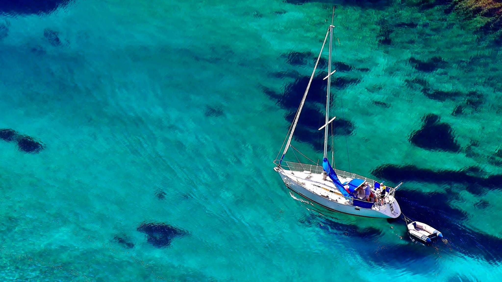 Sailboat on clear turquoise water with dinghy HD Wallpaper