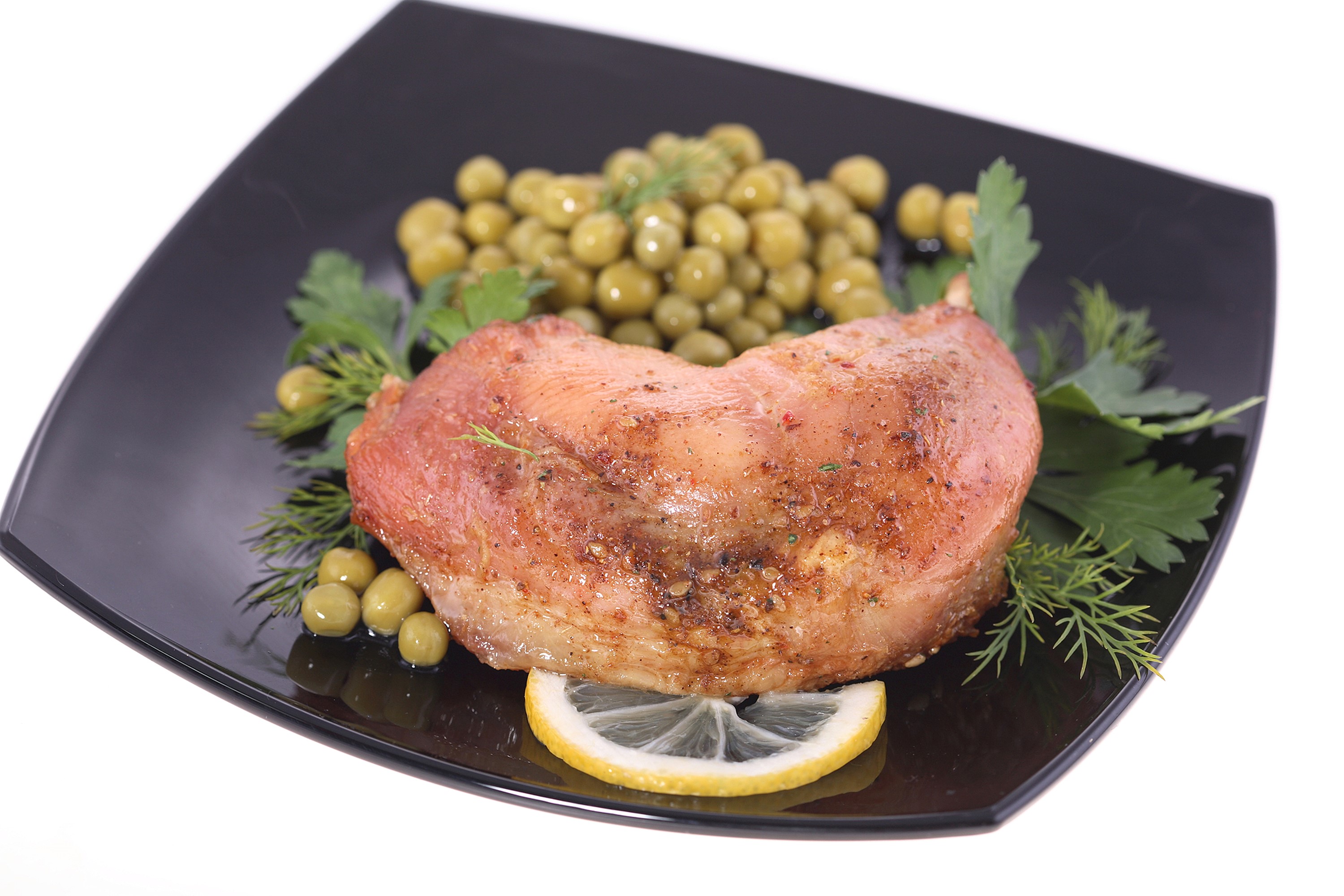 Roasted meat with peas, dill, and lemon on a black plate HD Wallpaper