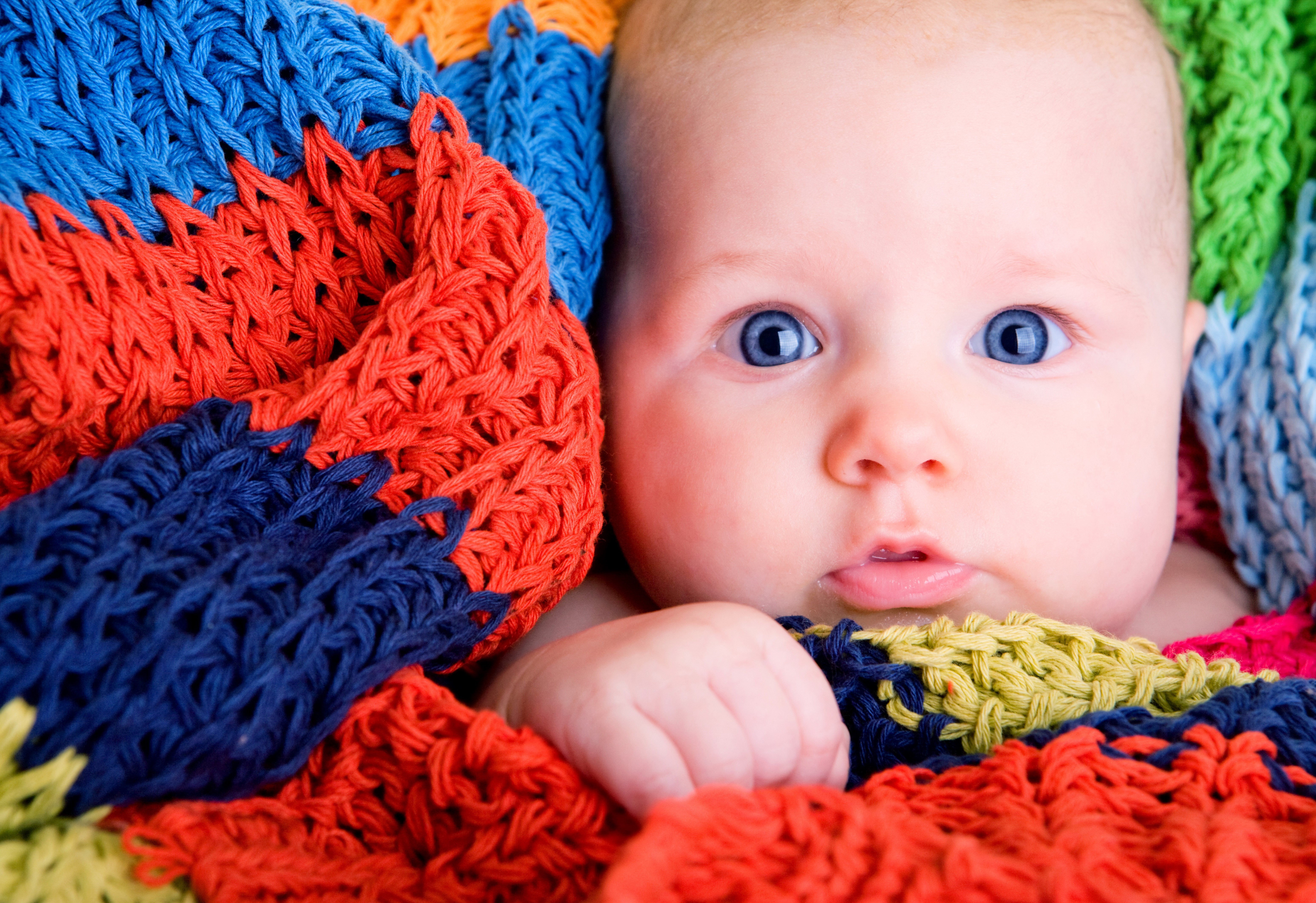 Baby with blue eyes wrapped in a colorful blanket HD Wallpaper