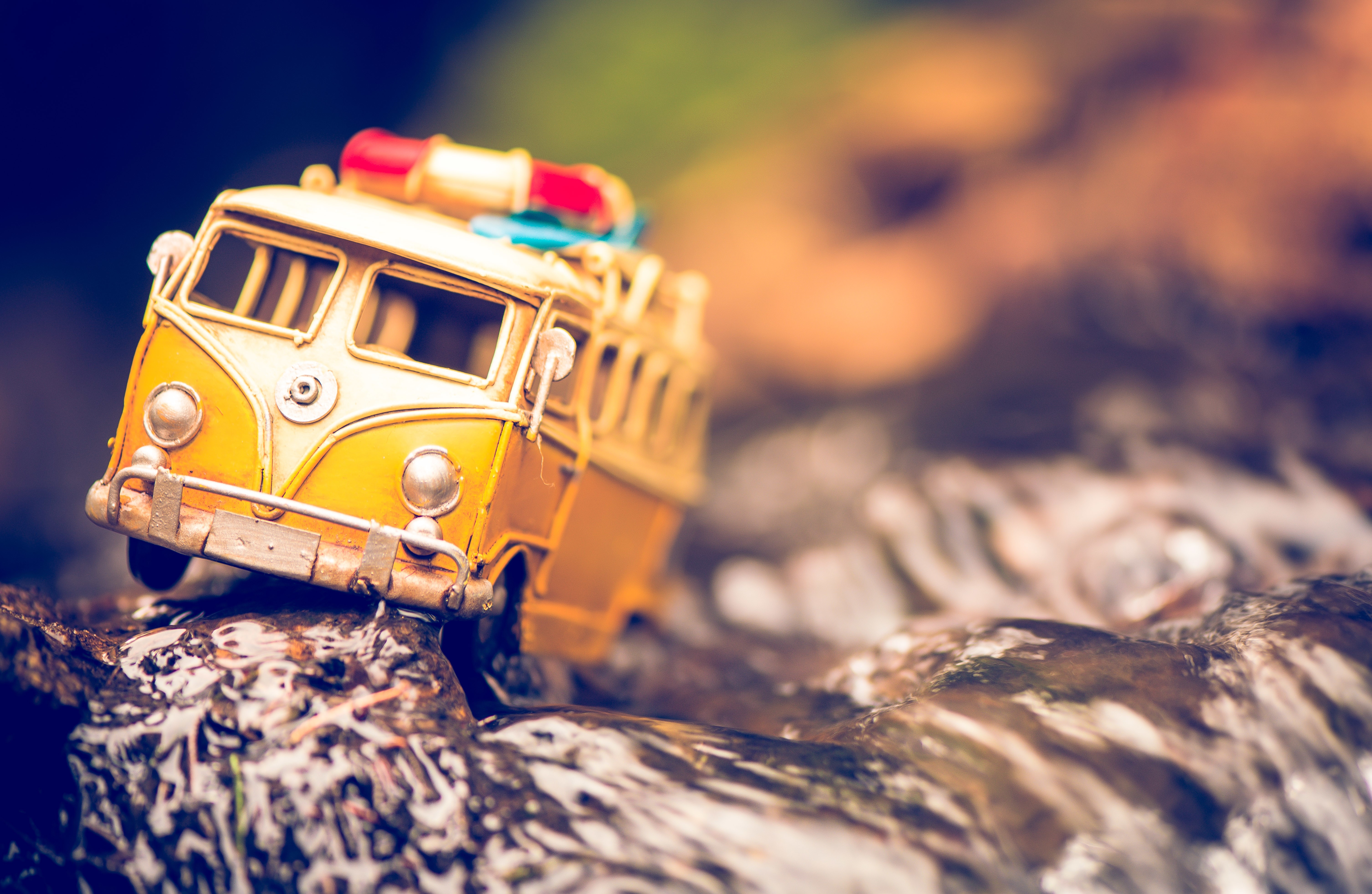 Yellow toy bus on rocks in water HD Wallpaper
