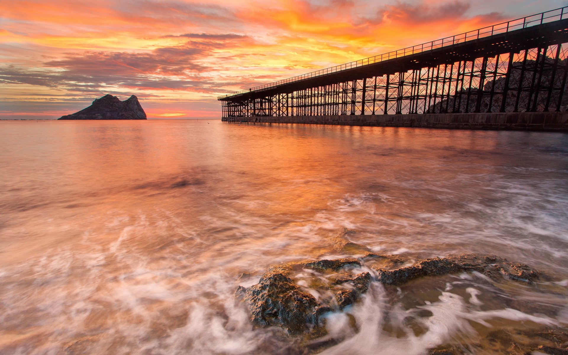 Sunset over the sea with a pier and island HD Wallpaper