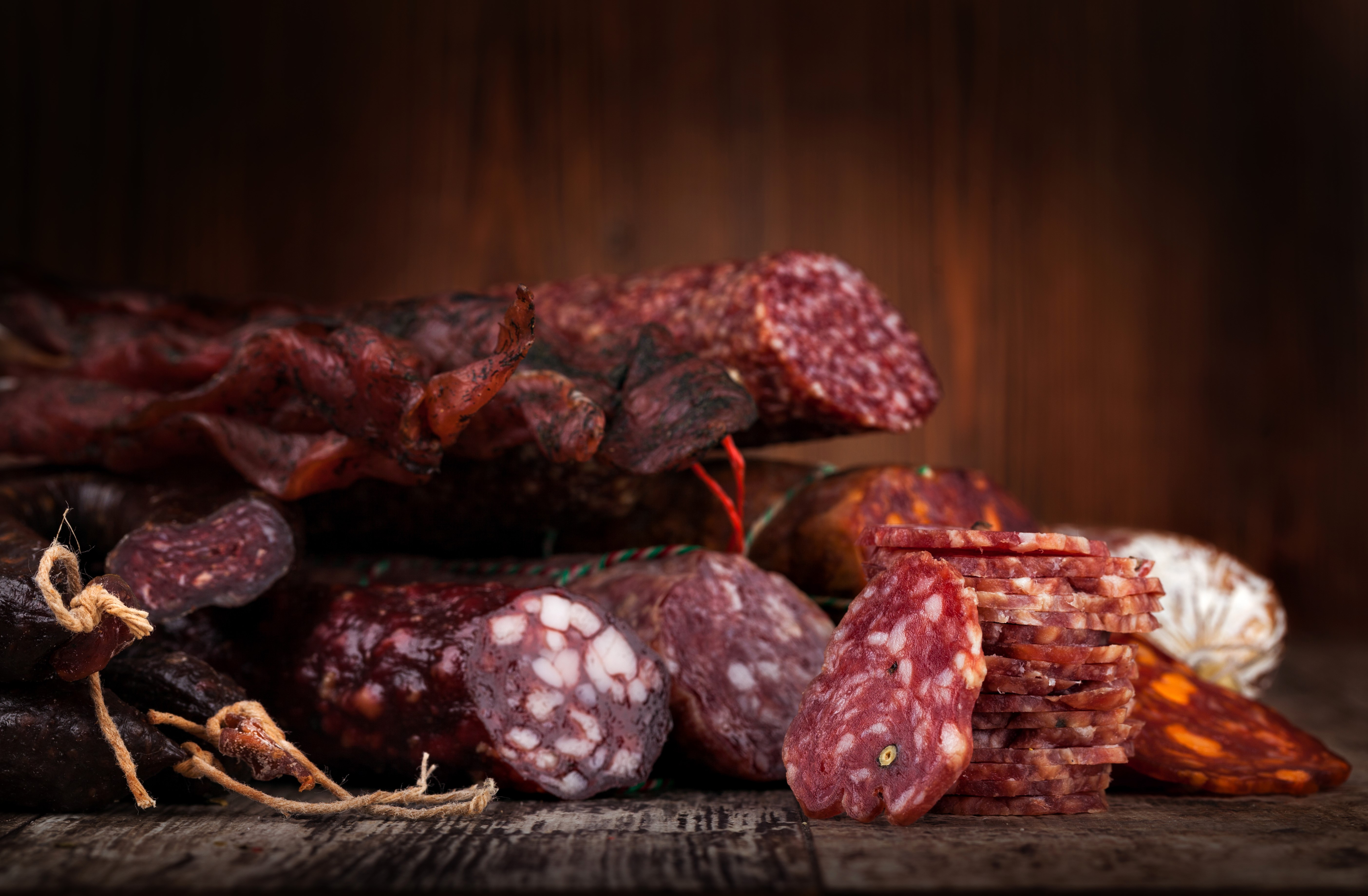 Assortment of cured sausages on a wooden surface HD Wallpaper