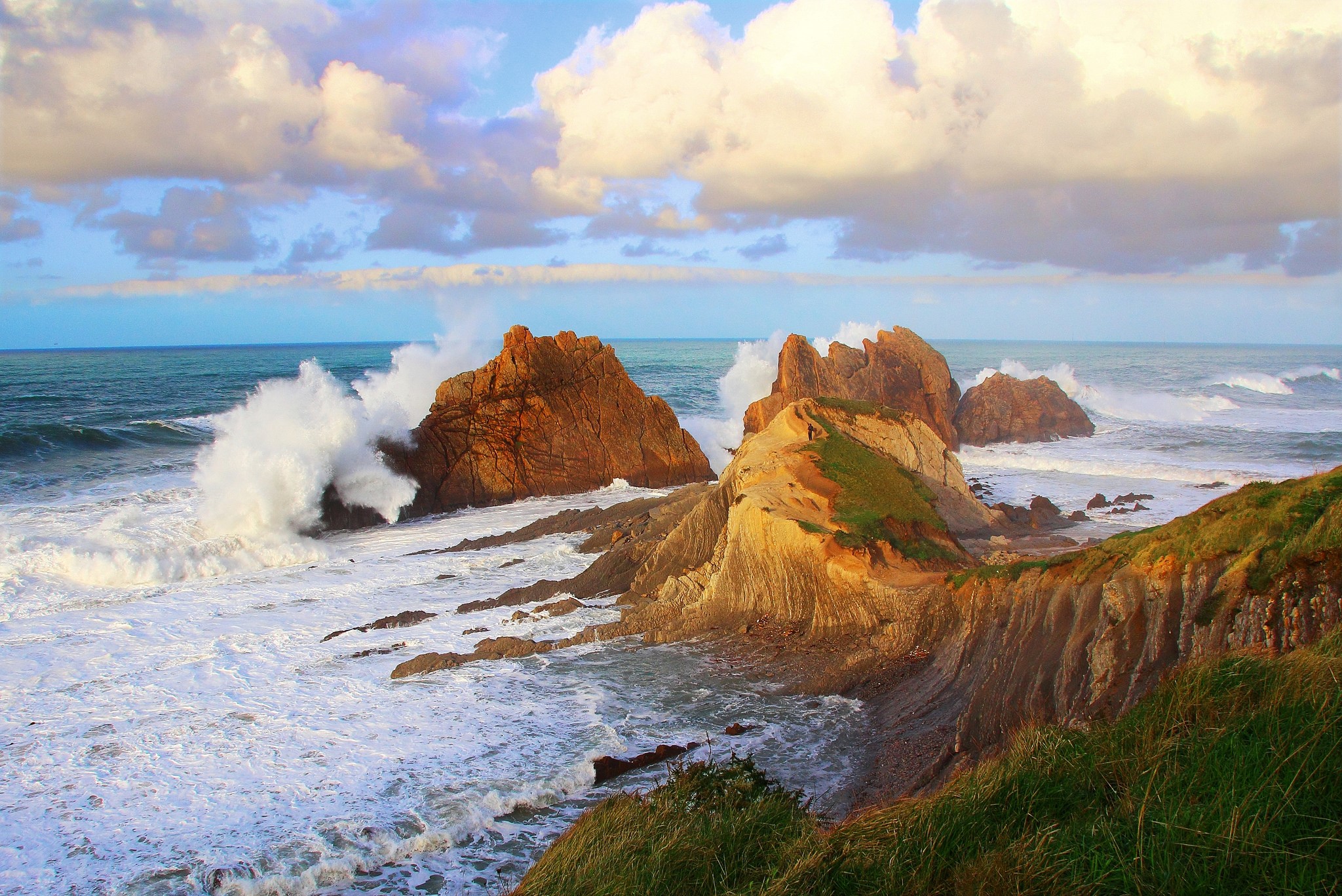 Waves crashing on rocky coast with clouds HD Wallpaper