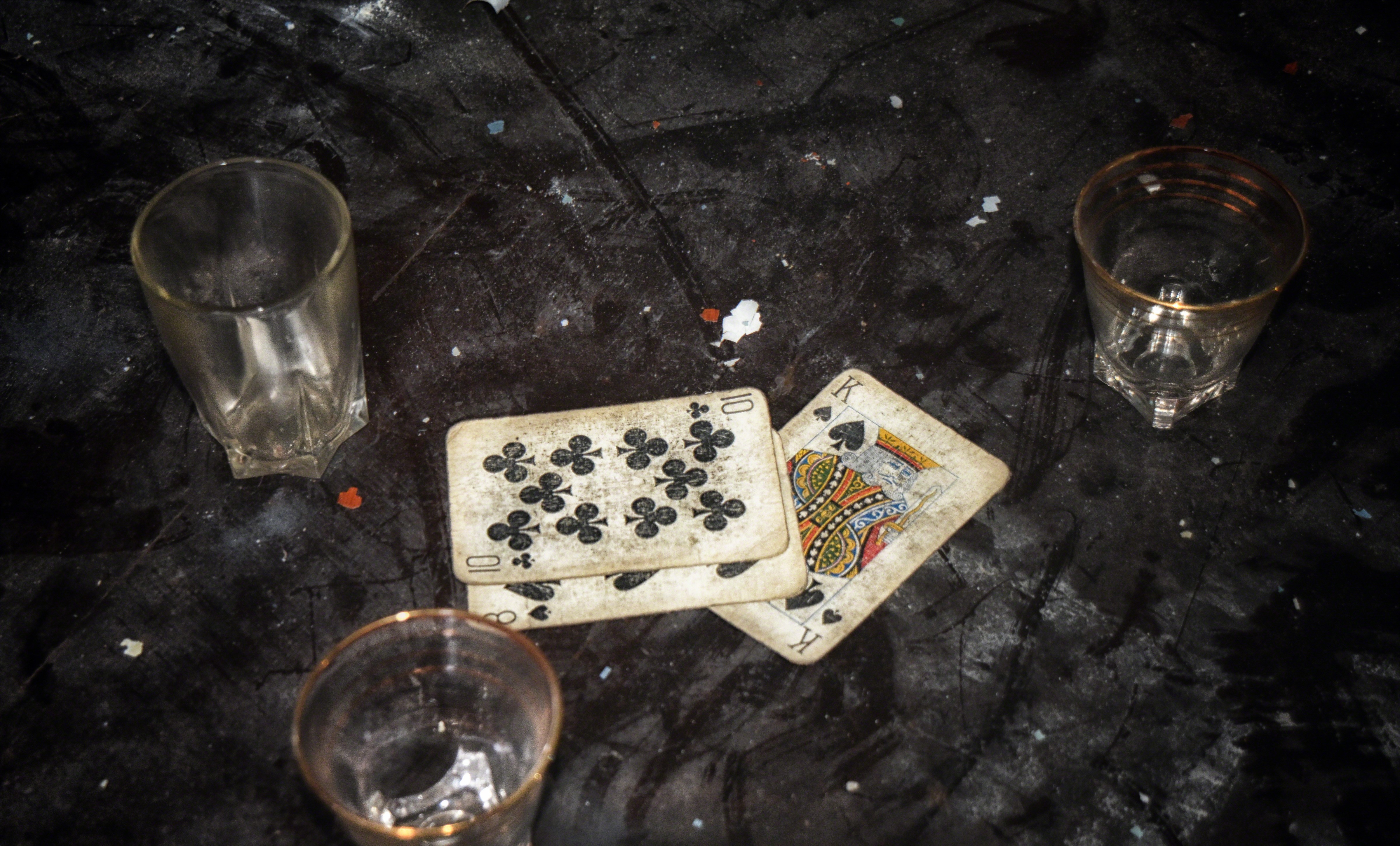Playing cards and shot glasses on a dark surface HD Wallpaper
