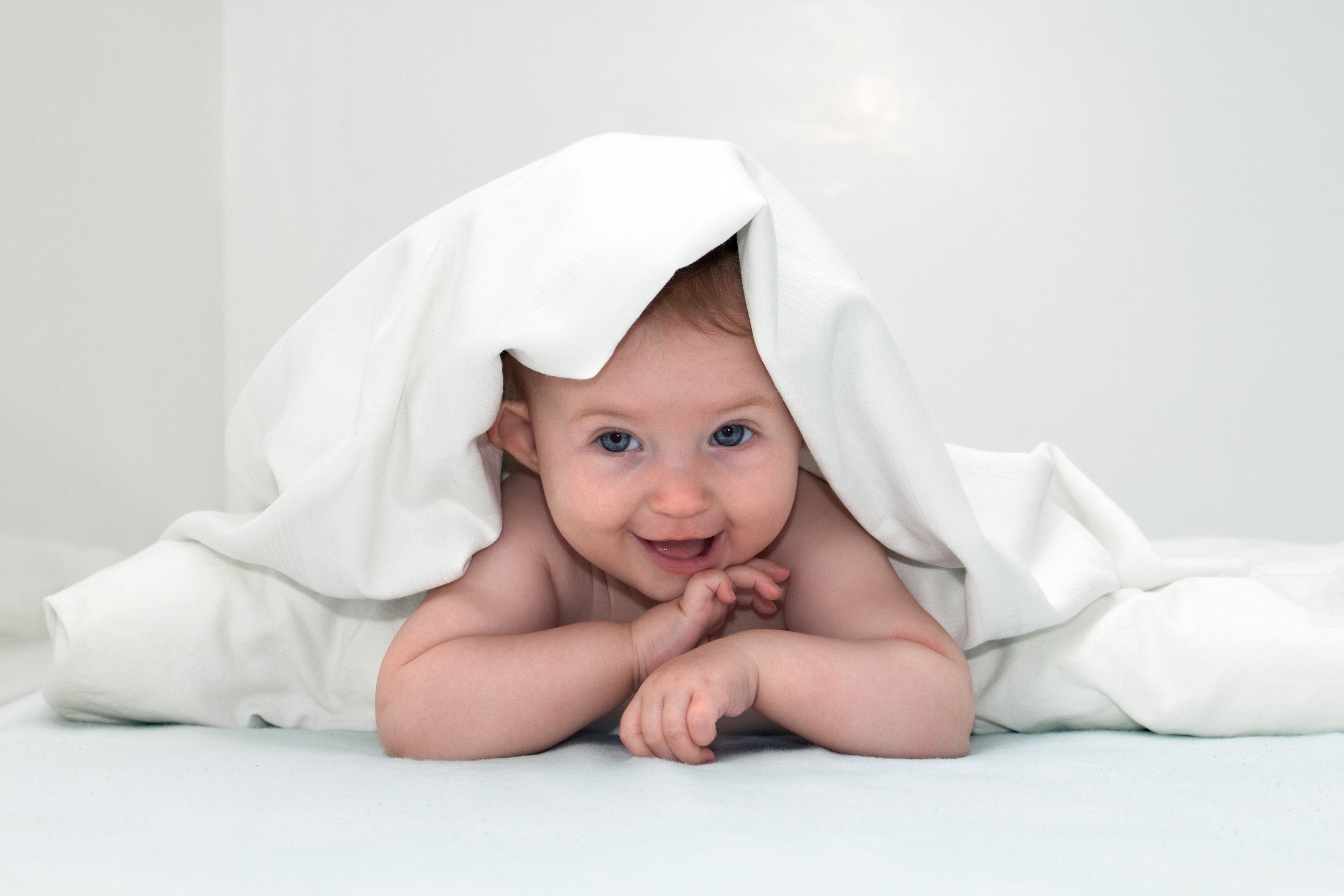 Baby peeking from under a white blanket HD Wallpaper