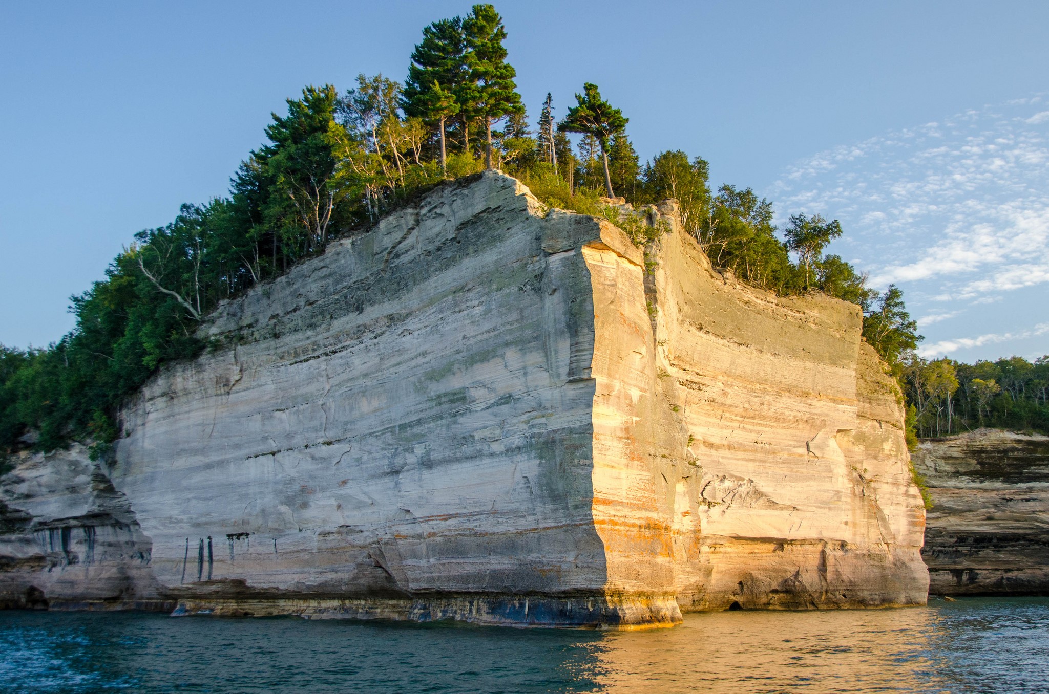 Cliff face with trees and water HD Wallpaper