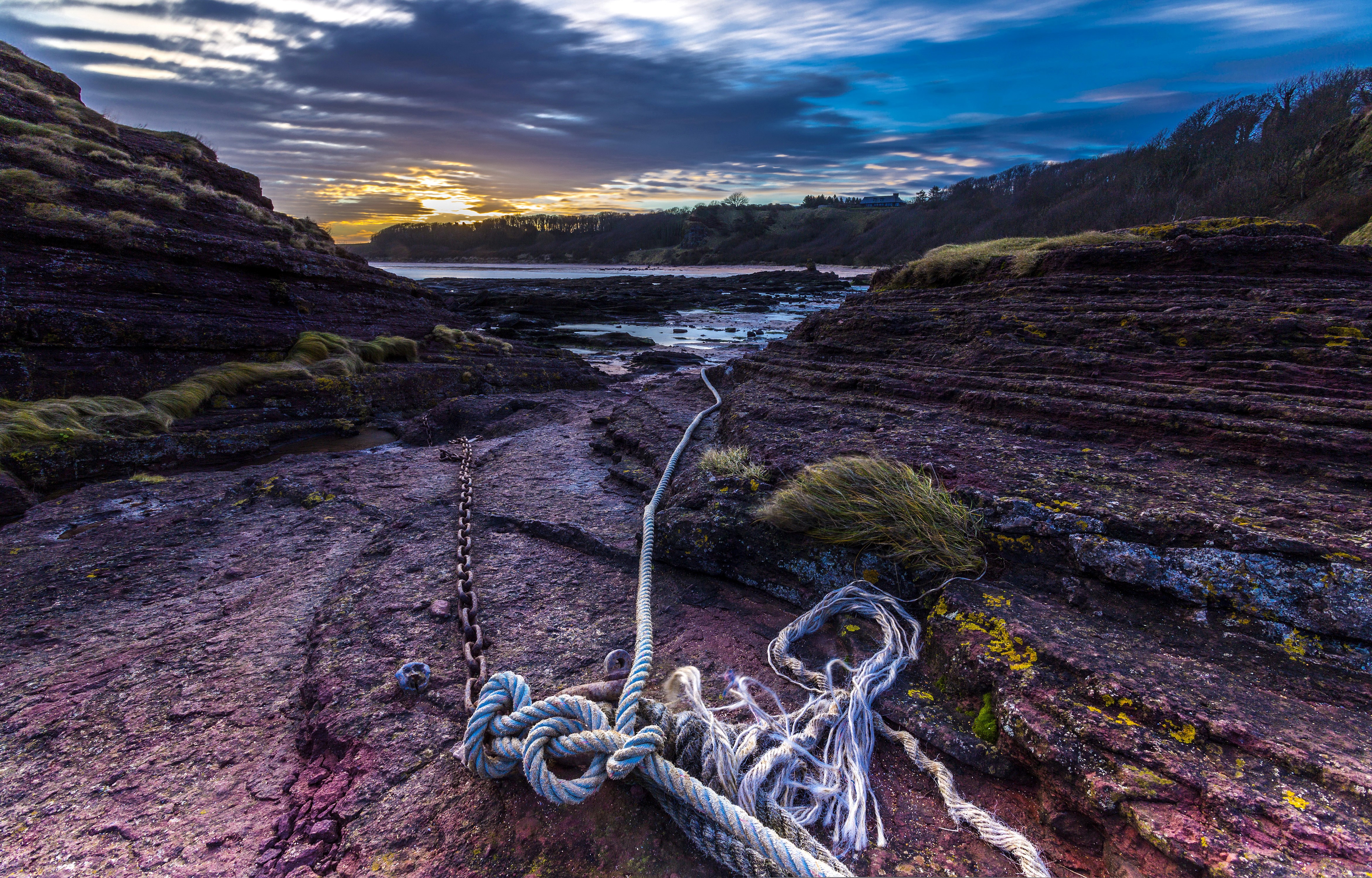 Rope and chain on rocky shore at sunset HD Wallpaper