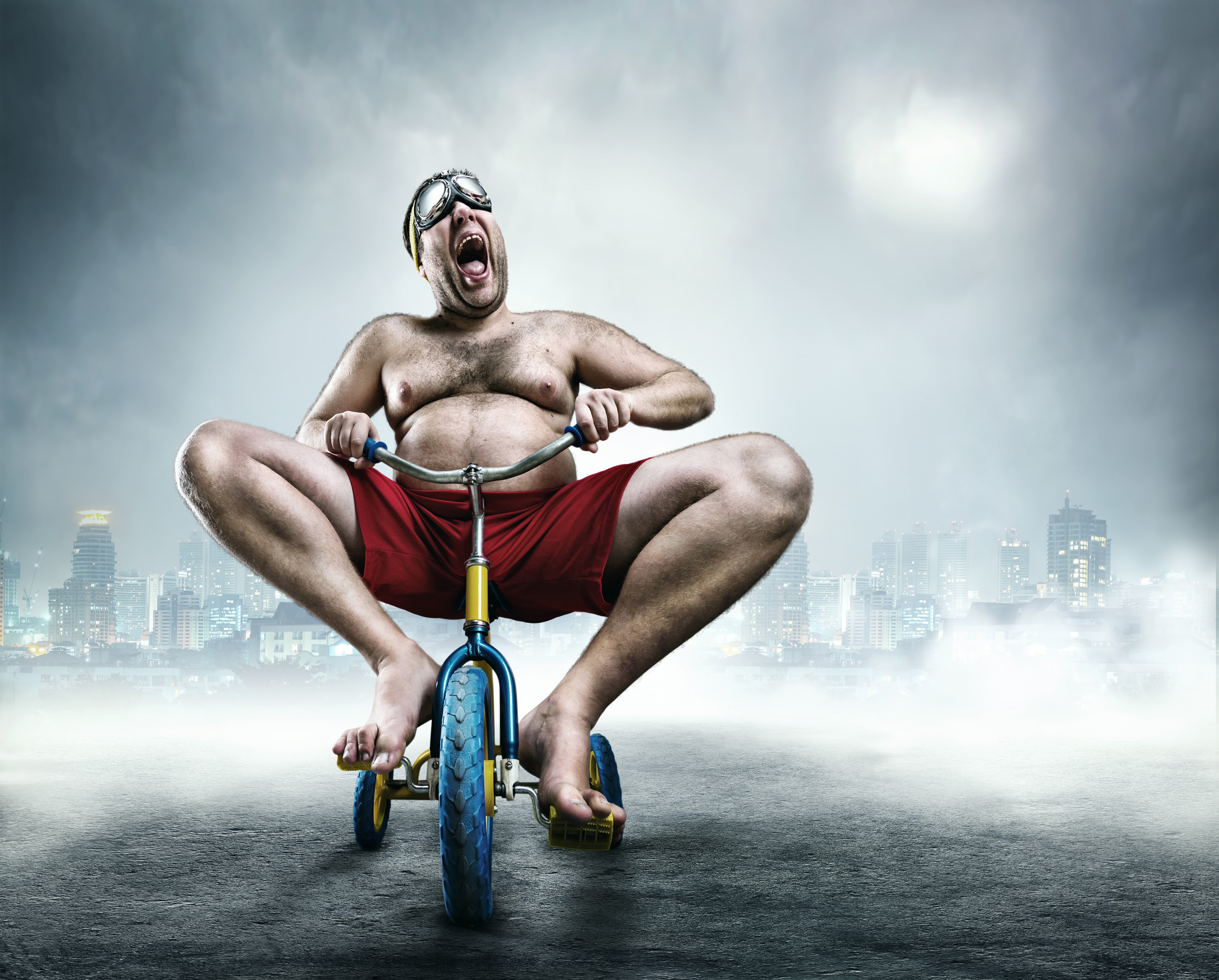 Man in goggles riding a tricycle in a city HD Wallpaper