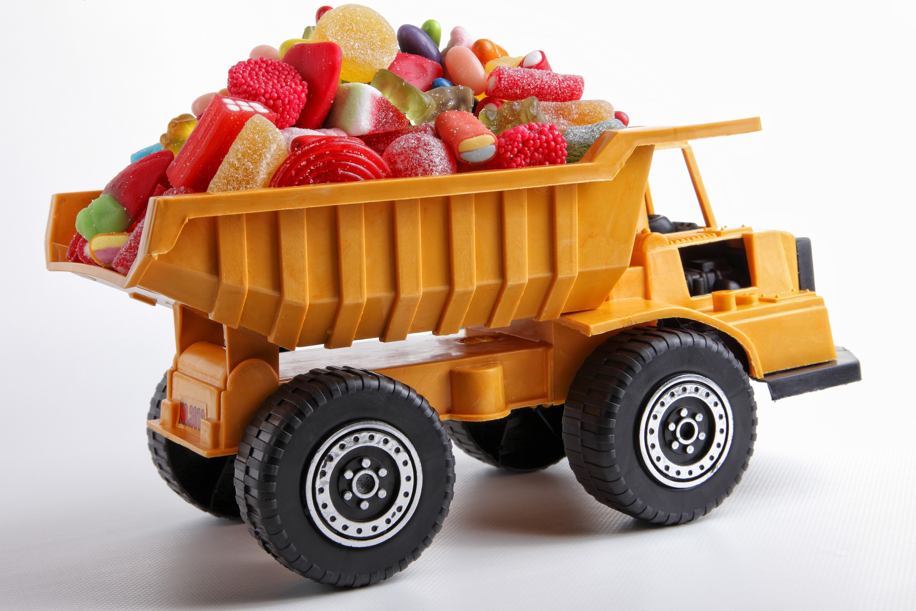 Yellow toy dump truck filled with assorted candies HD Wallpaper