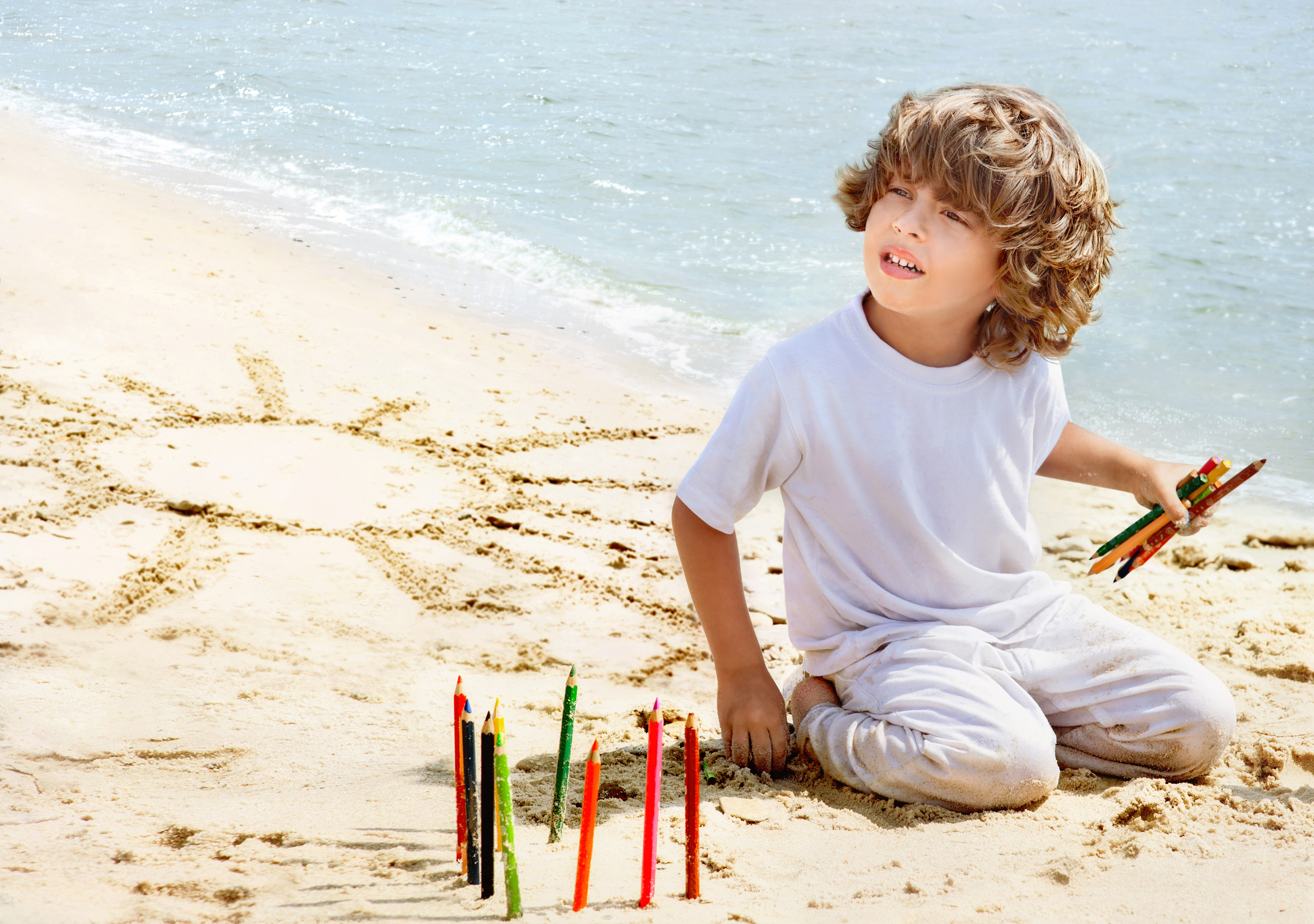 Boy drawing sun on beach with crayons HD Wallpaper