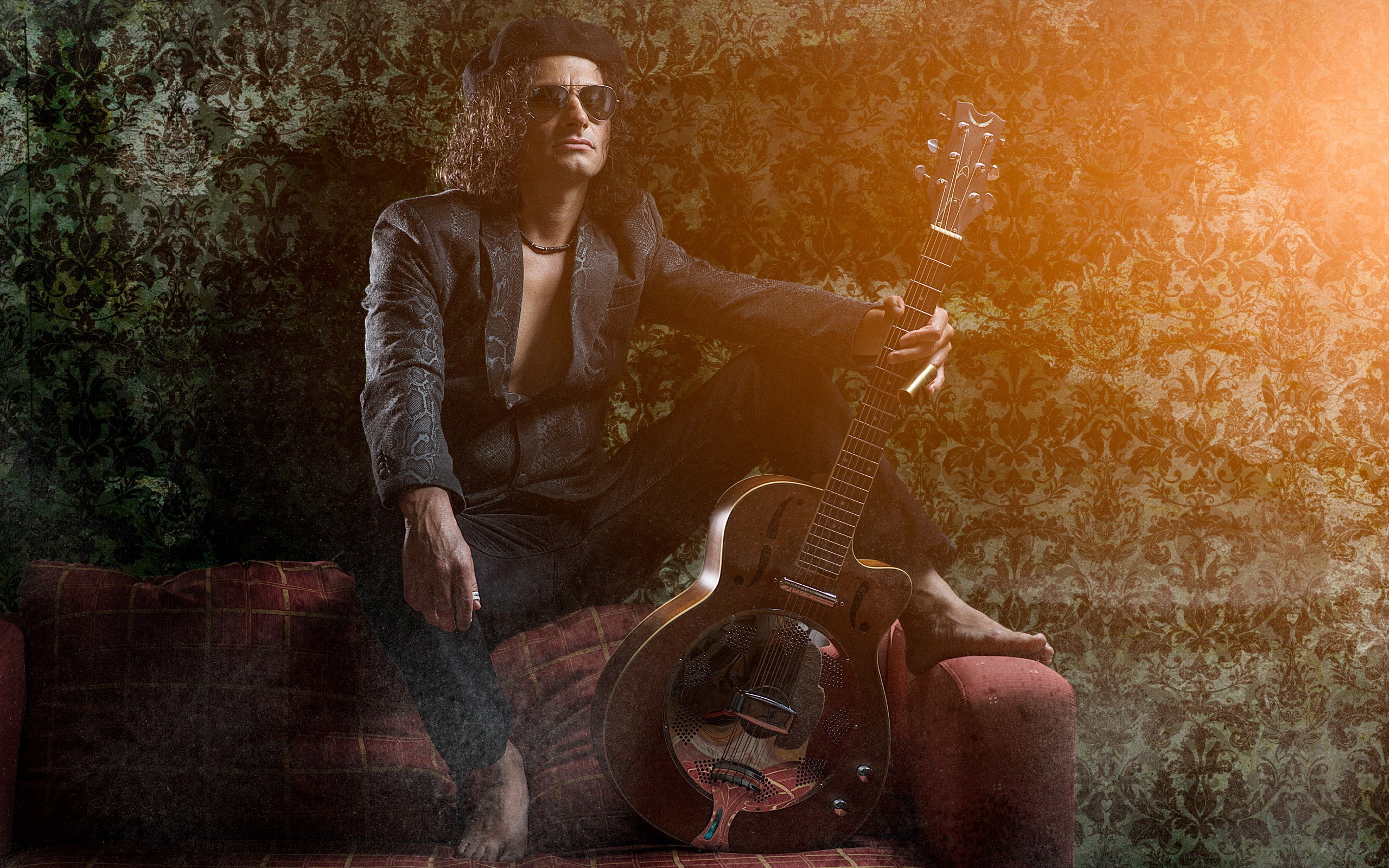 Man with guitar sitting on a sofa HD Wallpaper