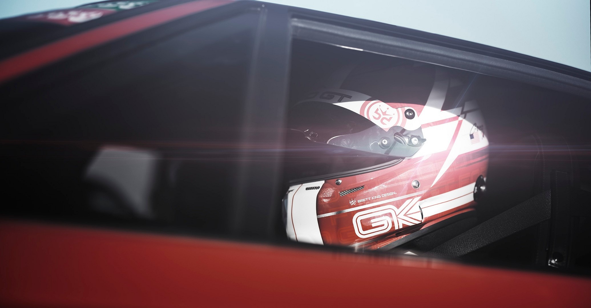 Red and white racing helmet inside a car HD Wallpaper