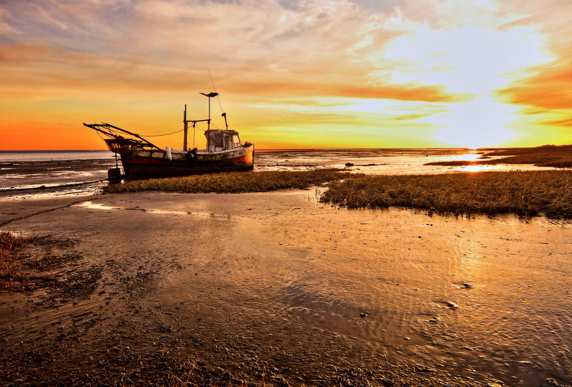 Fishing boat grounded on a beach at sunset HD Wallpaper