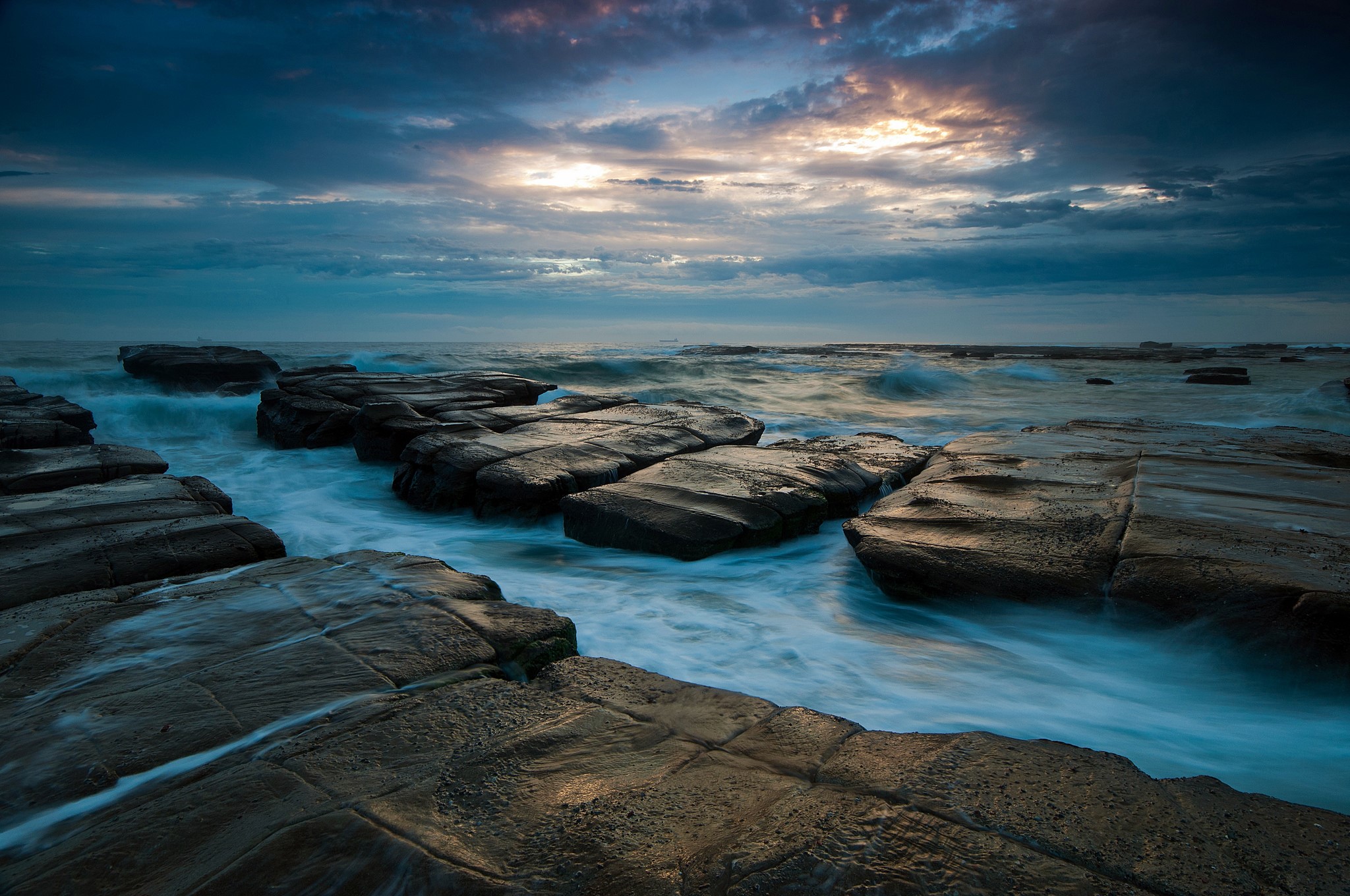 Ocean waves crashing on rocky shore at sunset HD Wallpaper