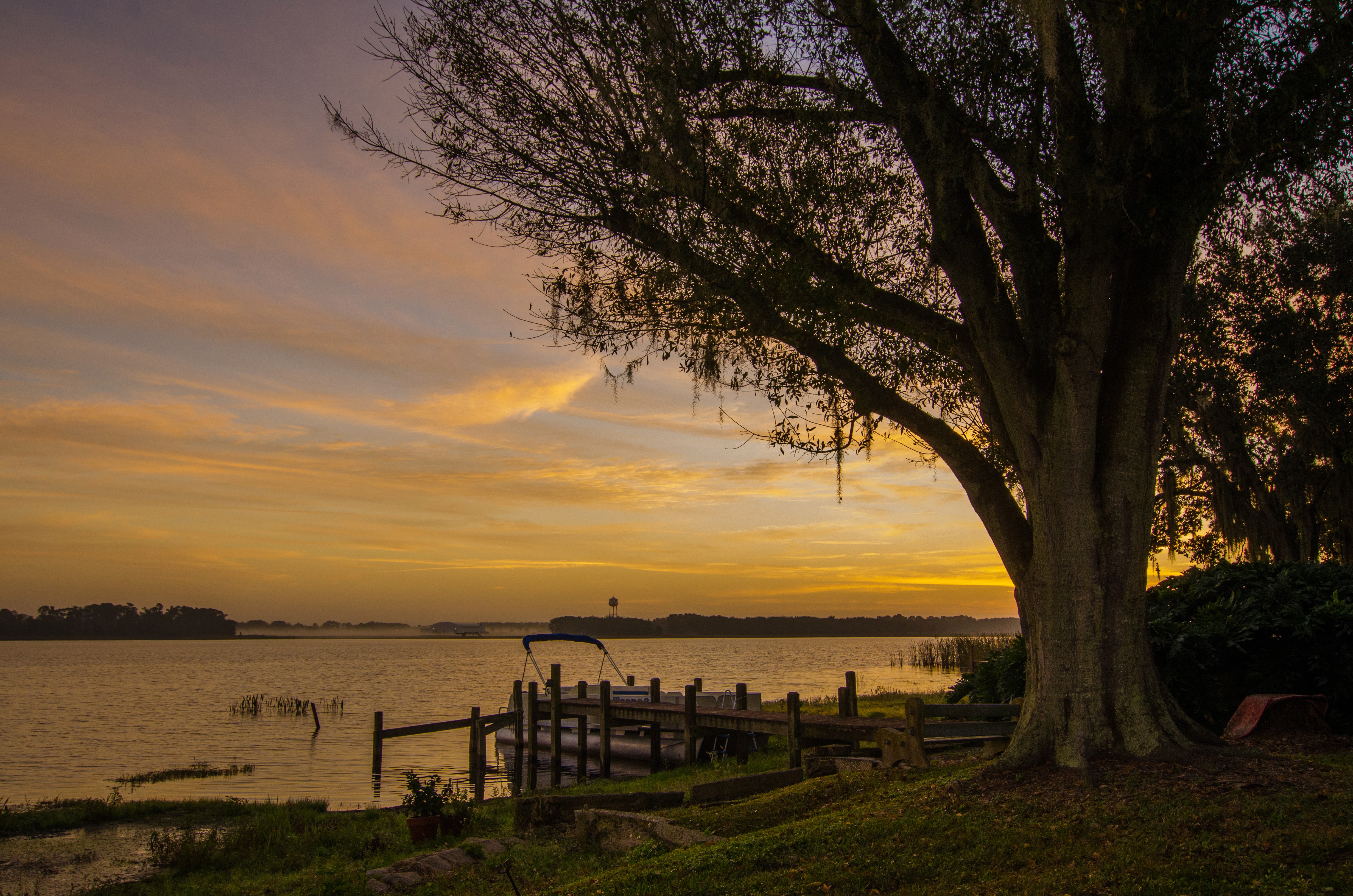 Sunset over a lake with a dock and boat HD Wallpaper