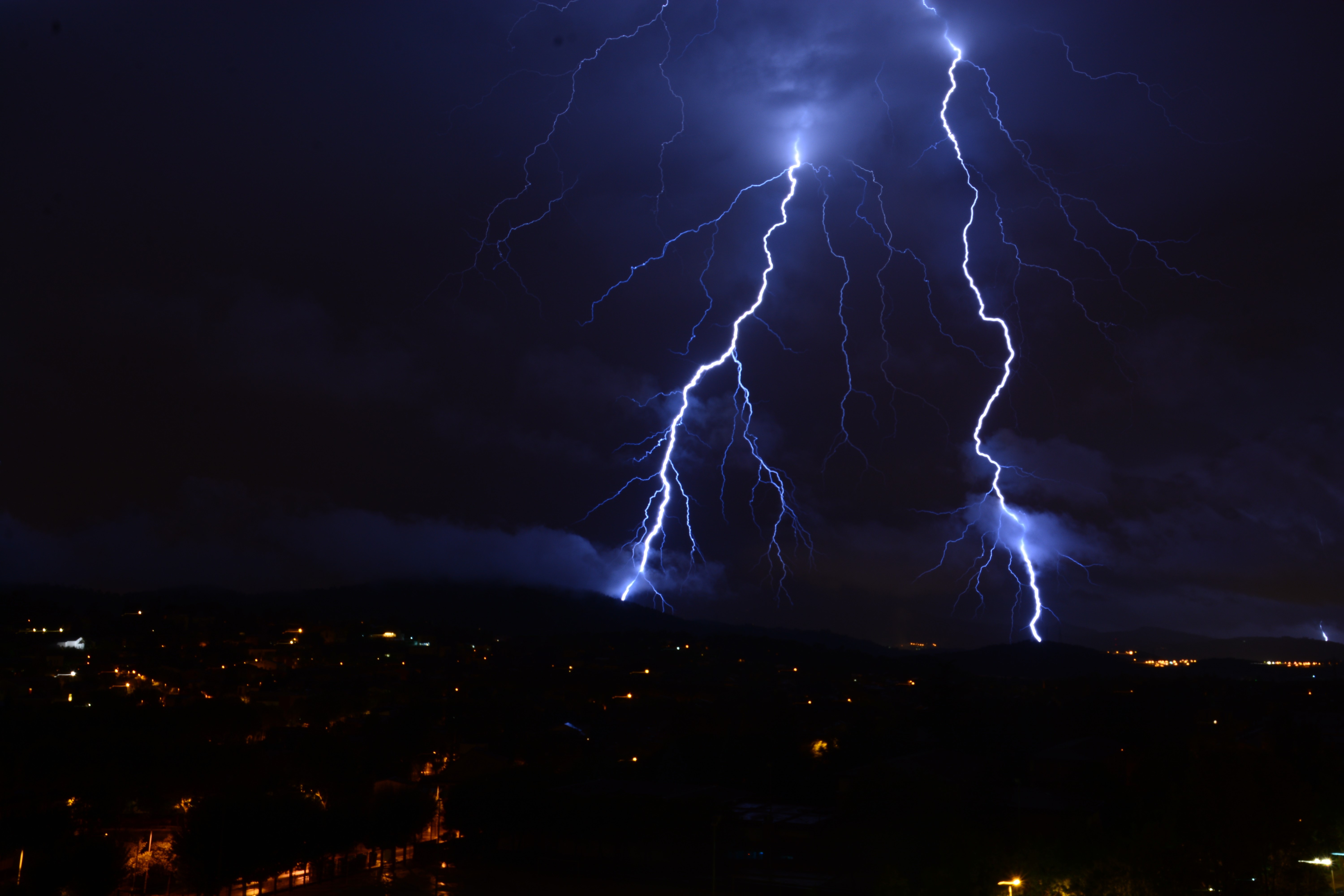 Lightning strikes over a city at night HD Wallpaper