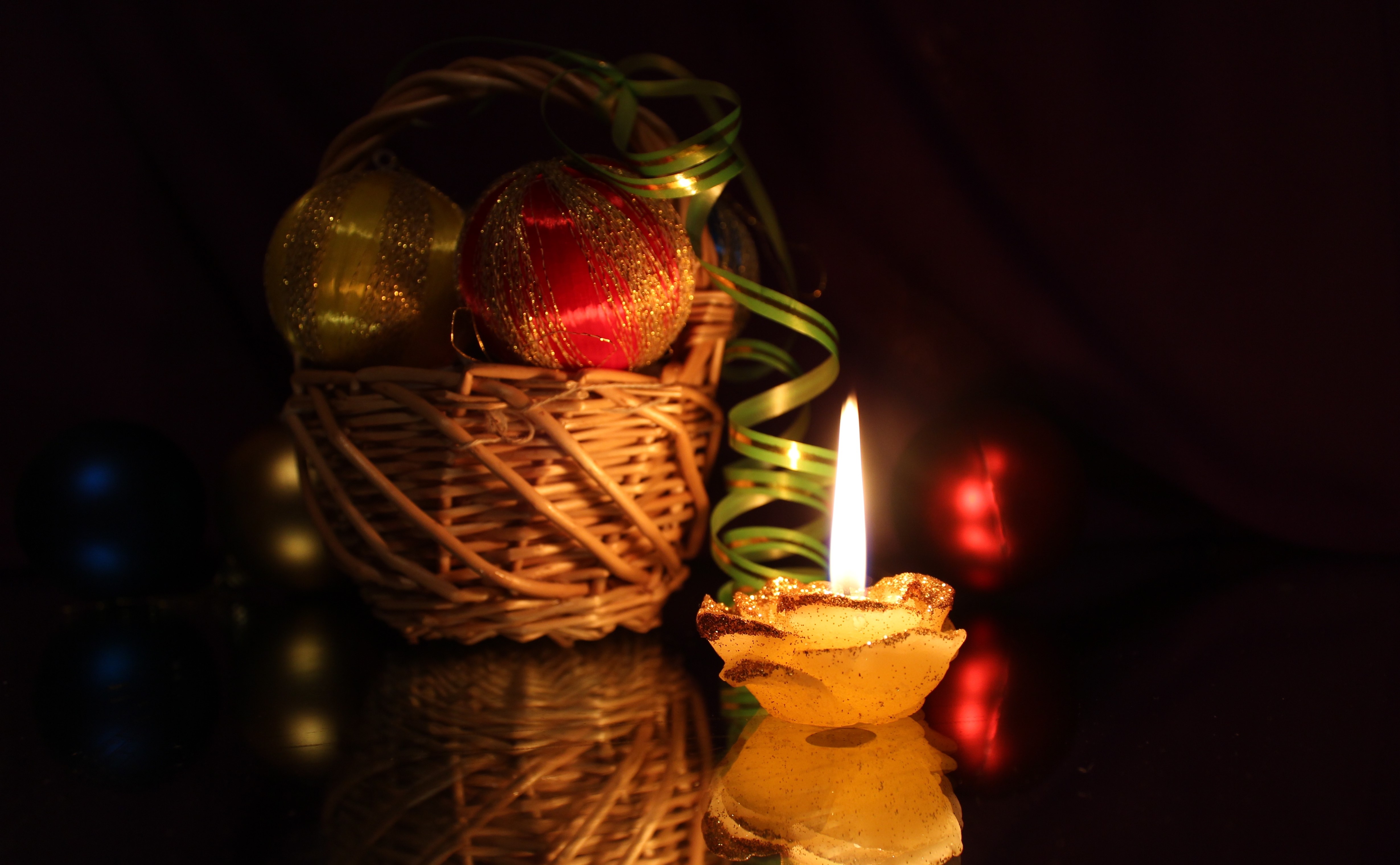 Christmas ornaments in a basket with a lit candle HD Wallpaper