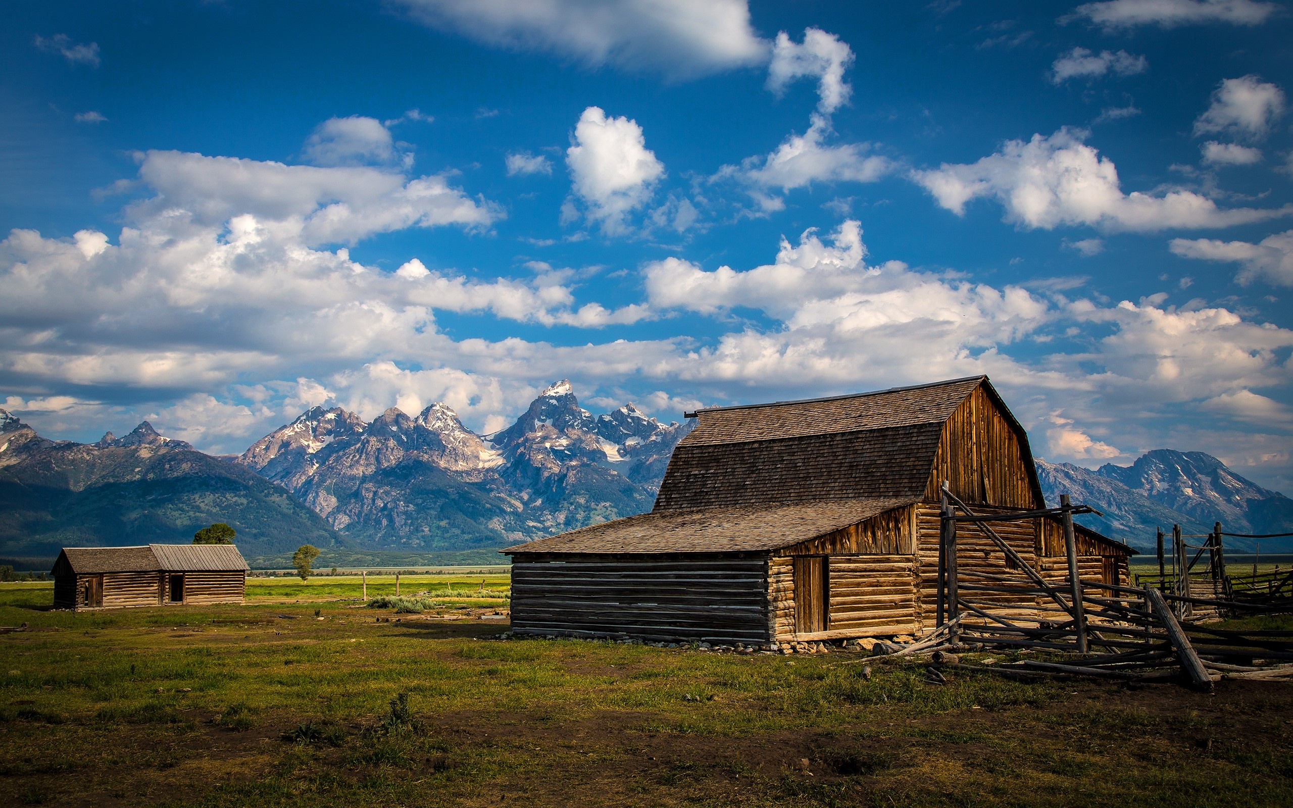 Wooden barns and mountains under a cloudy sky HD Wallpaper