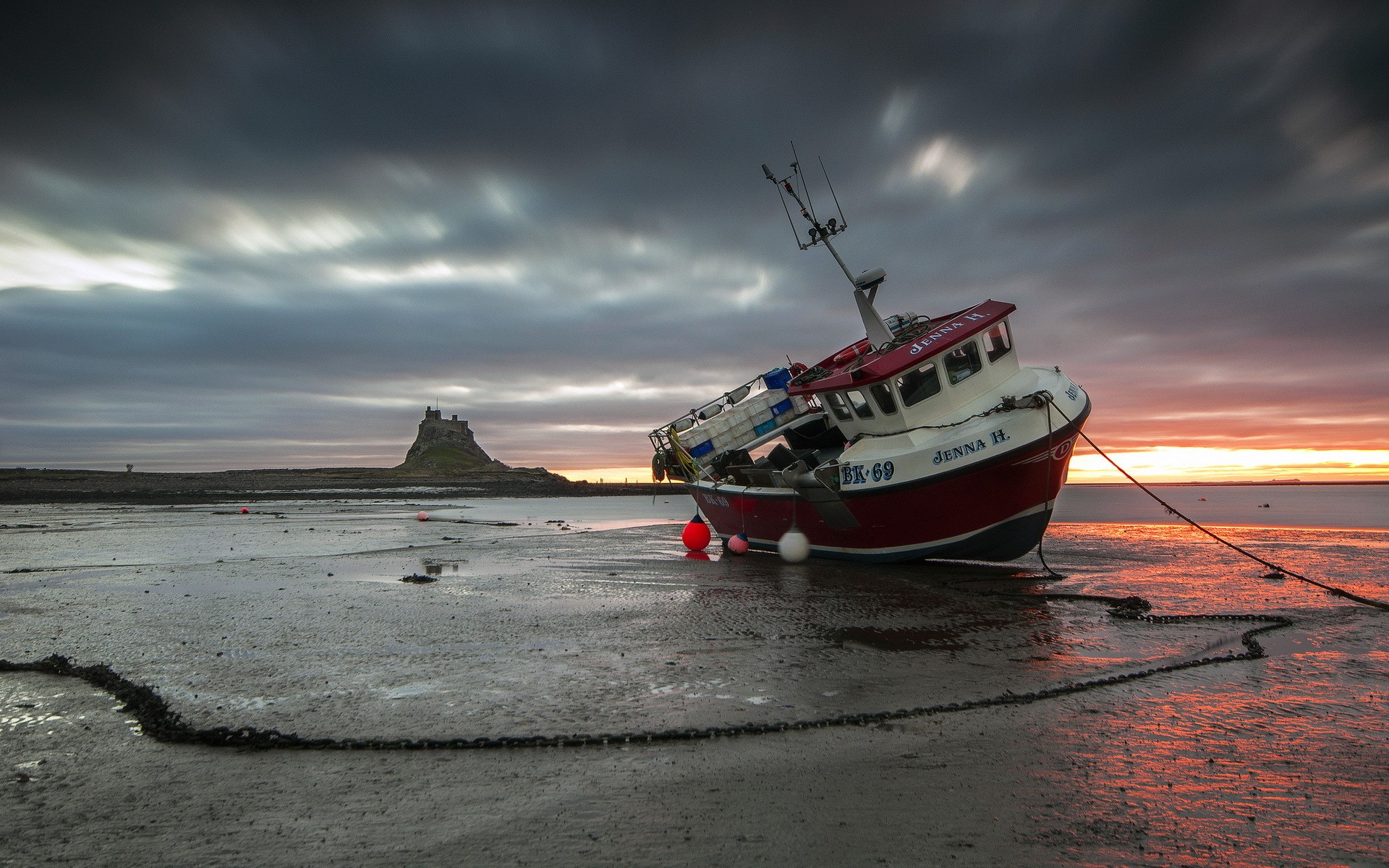 Fishing boat Jenna H. grounded on shore with Lindisfarne Castle in background HD Wallpaper