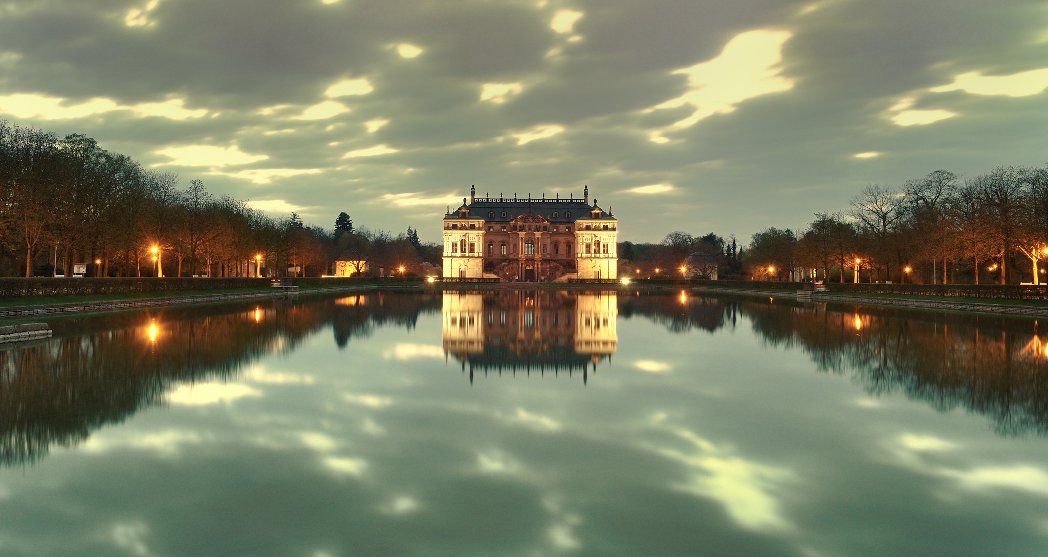 Palace reflected in a calm lake at dusk with illuminated trees HD Wallpaper