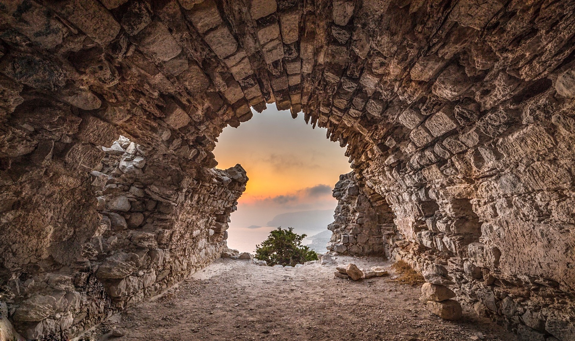 Stone archway overlooking a sunset over the sea HD Wallpaper