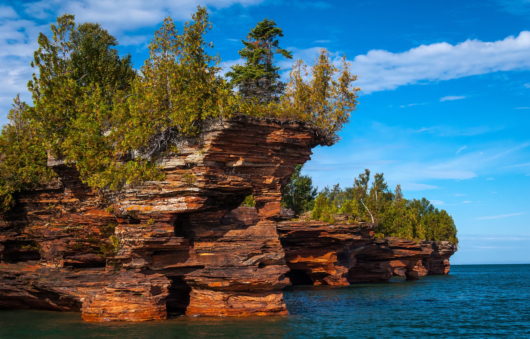 Red rock formations with trees on the water HD Wallpaper